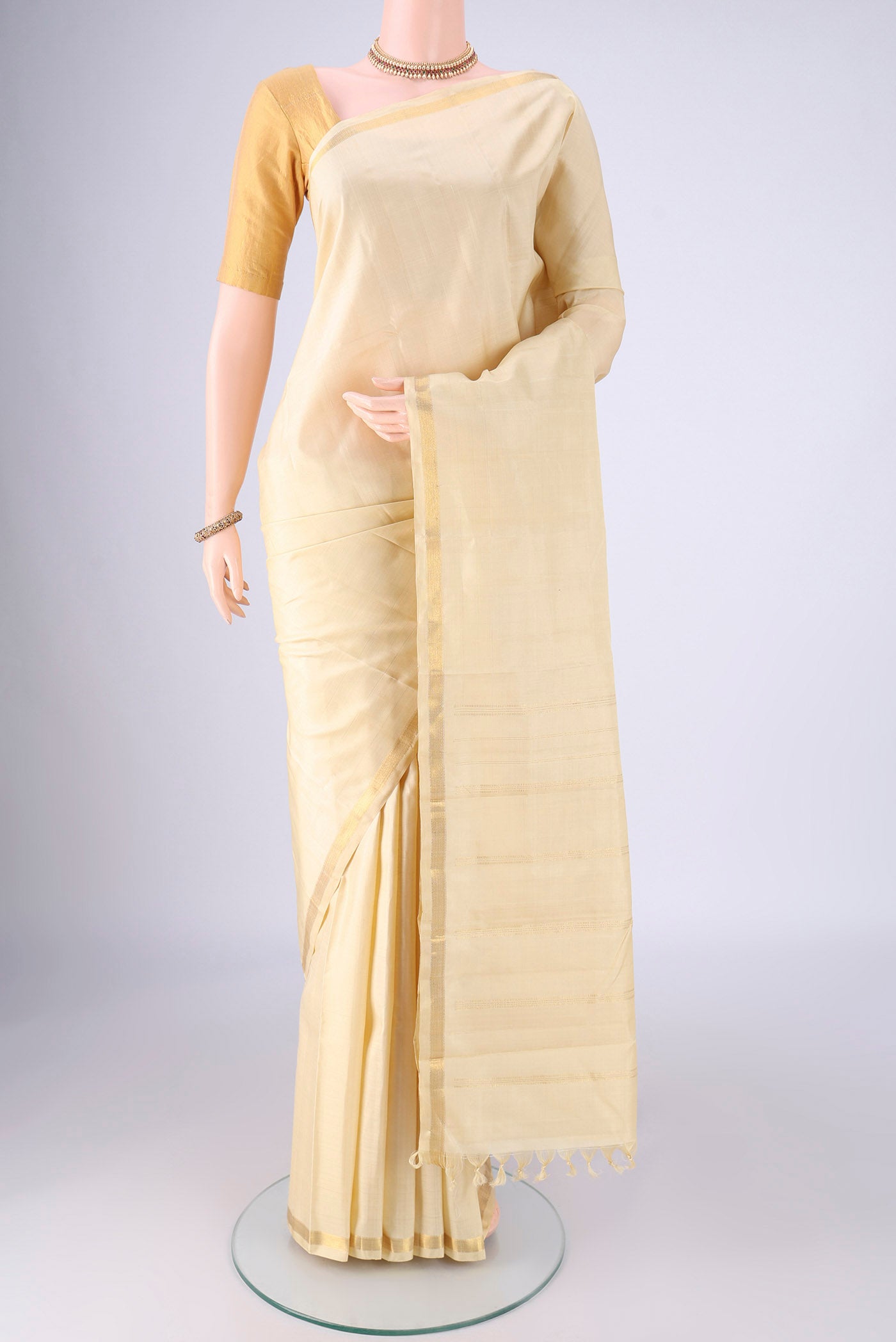 Cream Kanjivaram Silk Saree with Plain Body and Zari Border.  displayed on a mannequin