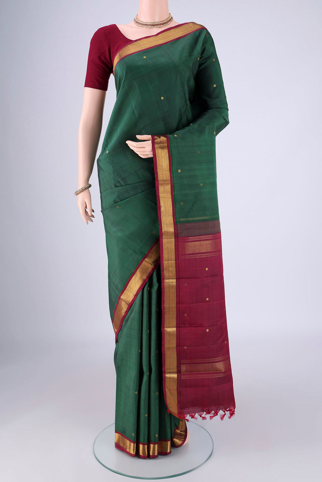 Bottle Green Kanjivaram Silk Saree with Zari Butta on the body and Zari Border.  displayed on a mannequin