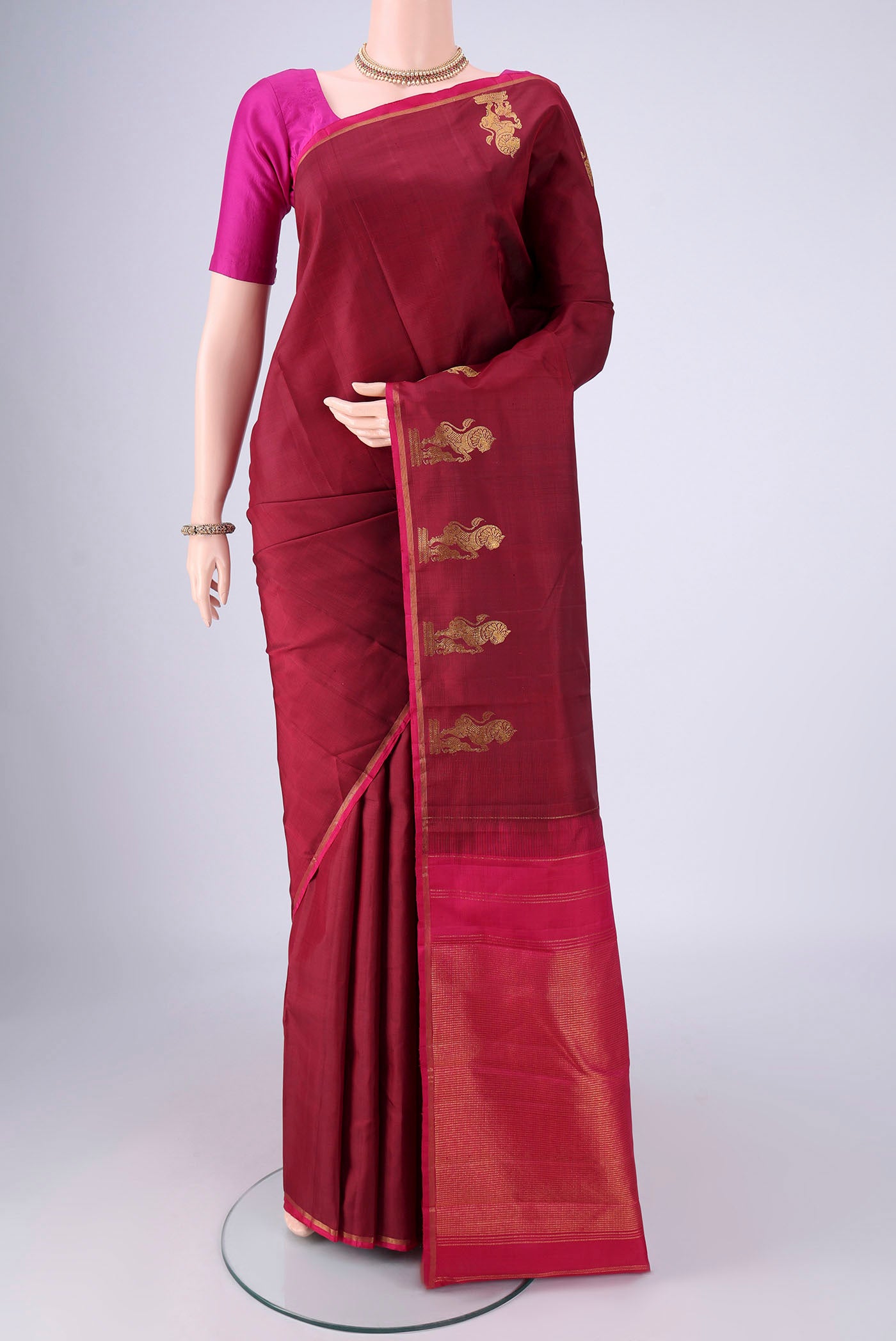 Maroon Kanchipuram Silk Saree with Plain Body and Zari Border.  displayed on a mannequin