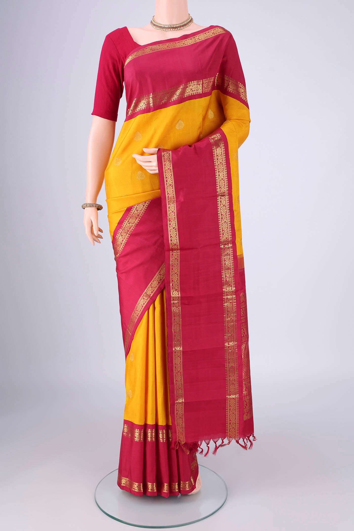 Yellow Kanjivaram Silk Saree with Zari Butta on the body and Zari Border.  displayed on a mannequin