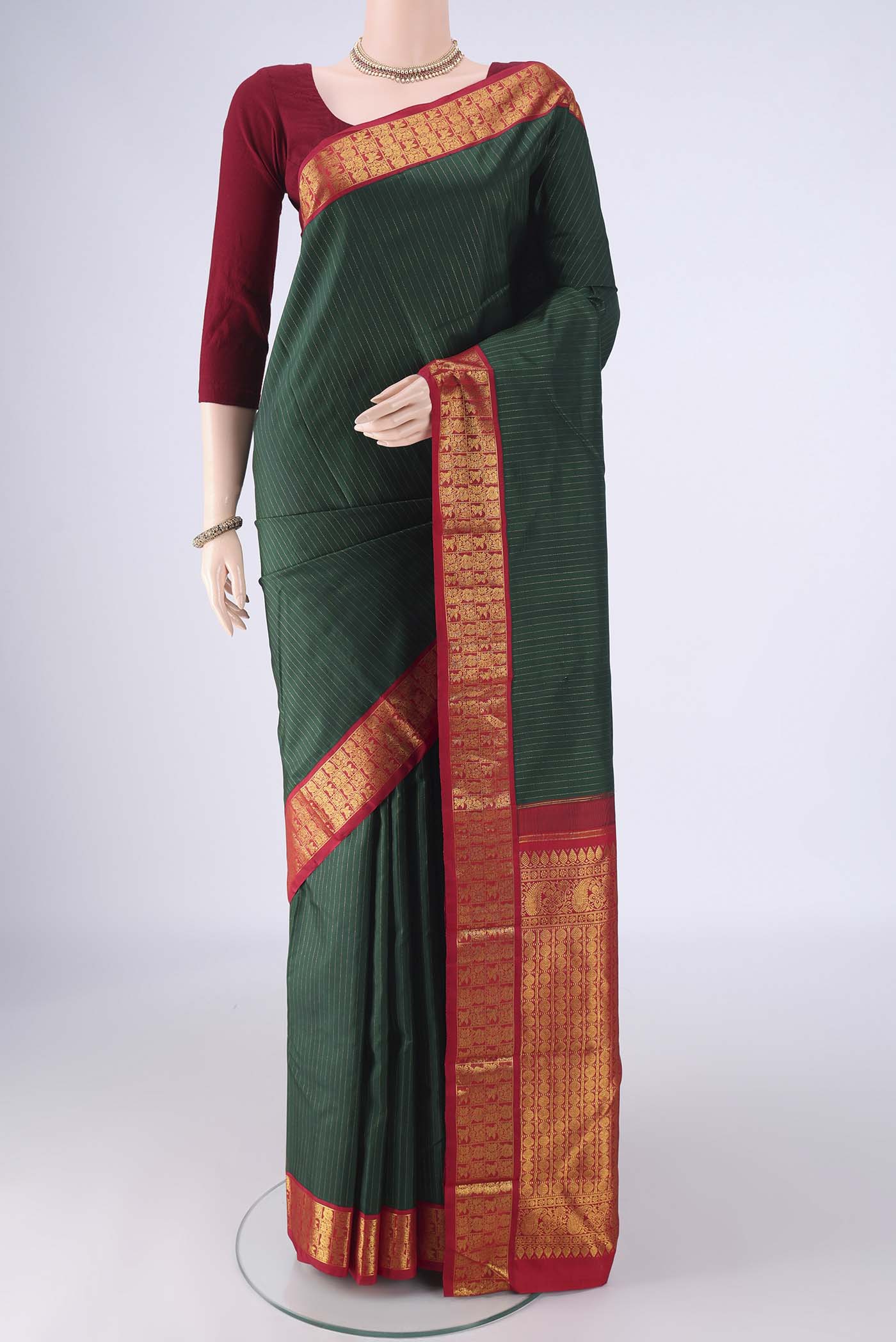 Bottle Green Kanjivaram Silk Saree with Stripes on the body and Zari Border.  displayed on a mannequin