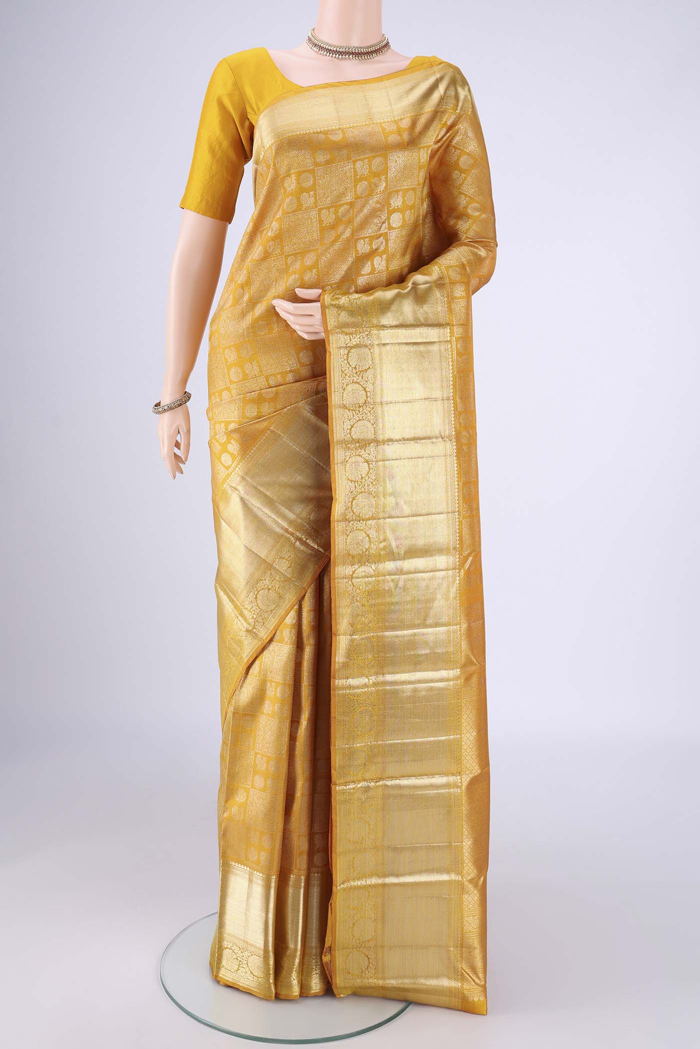 Mustard Kanchipuram Silk Saree with Zari Brocade on the body and Zari Border.  displayed on a mannequin