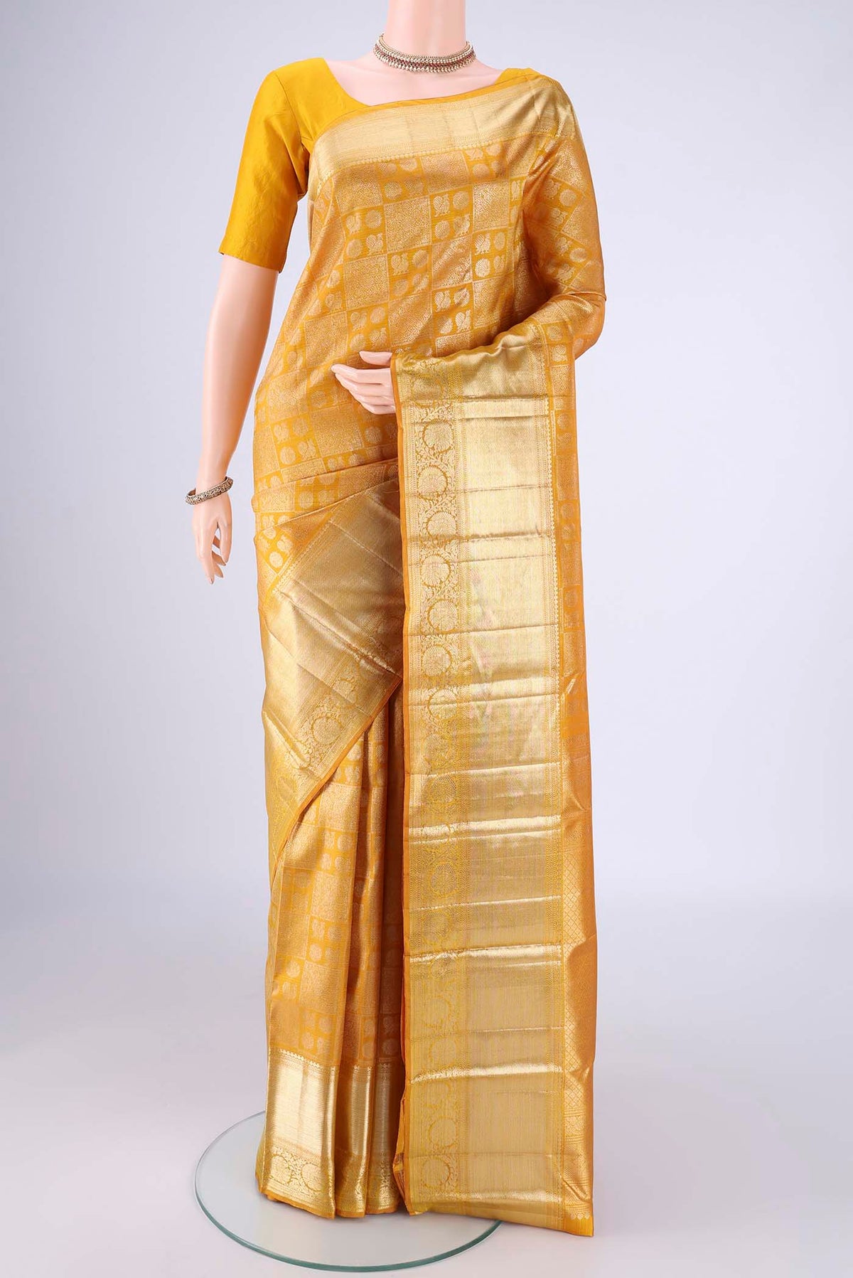 Mustard Kanchipuram Silk Saree with Zari Brocade on the body and Zari Border.  displayed on a mannequin