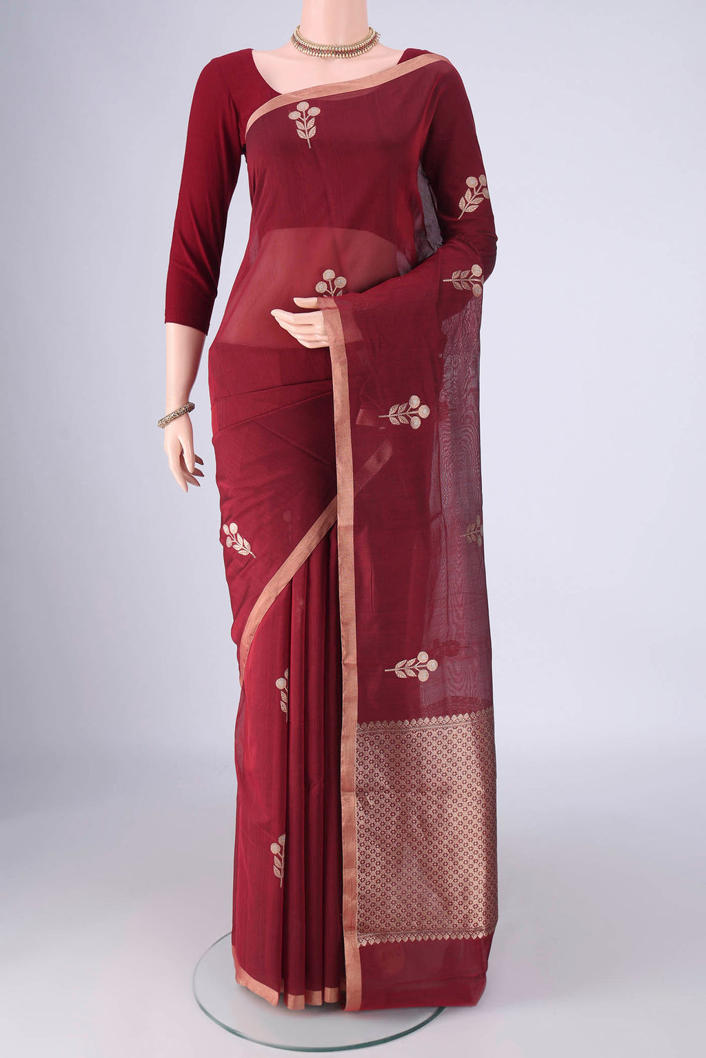 Maroon Banarasi Kora Cotton Saree with Zari Butta on the body and Zari Border.  displayed on a mannequin