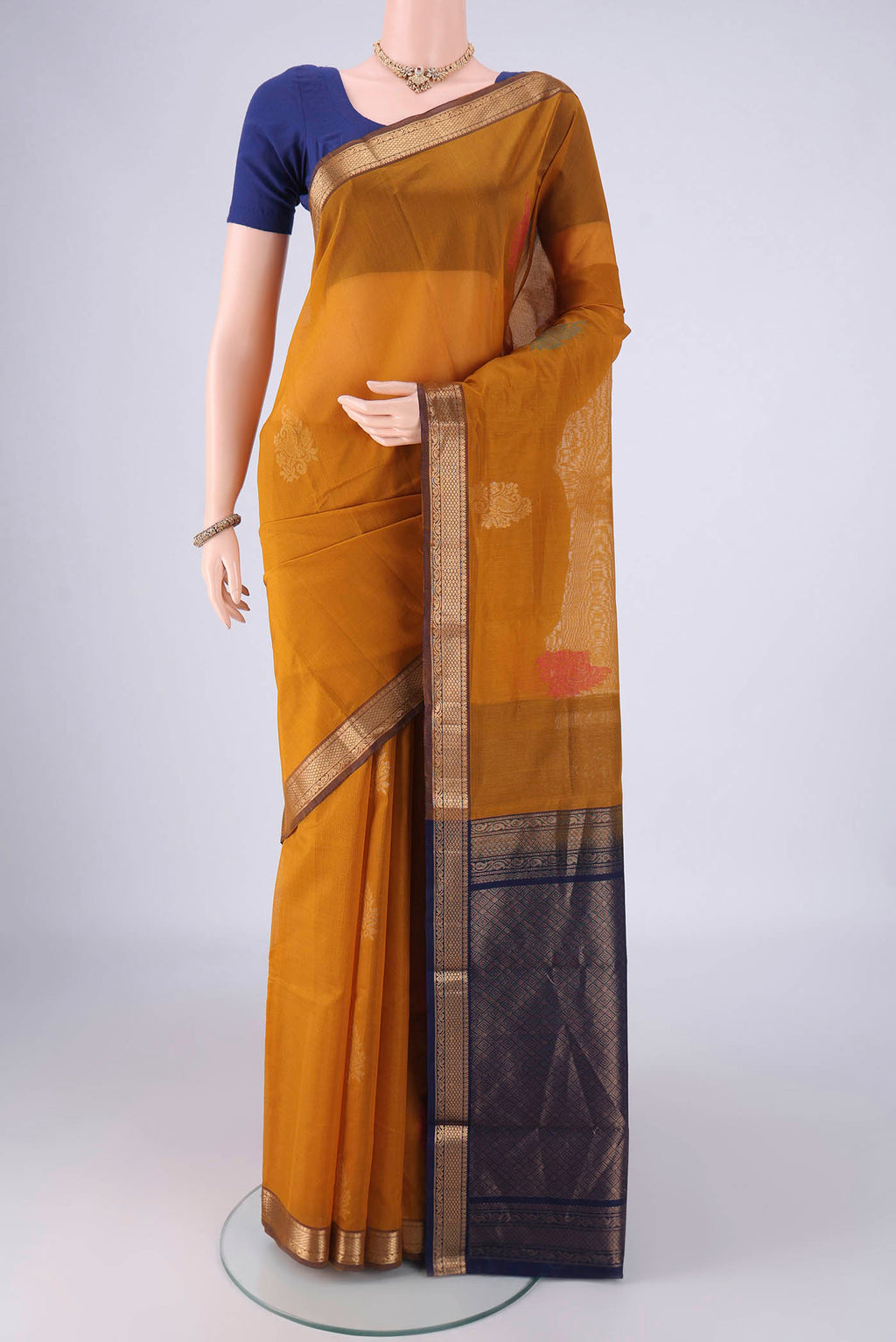 Mustard Silk Cotton Saree with Zari Butta on the body and Zari Border.  displayed on a mannequin
