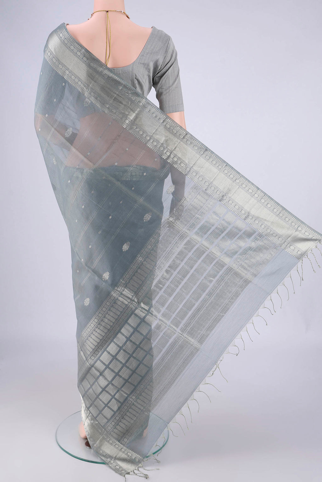 Flat view of Grey Silk Cotton Saree with Zari Butta on the body and Zari Border. 