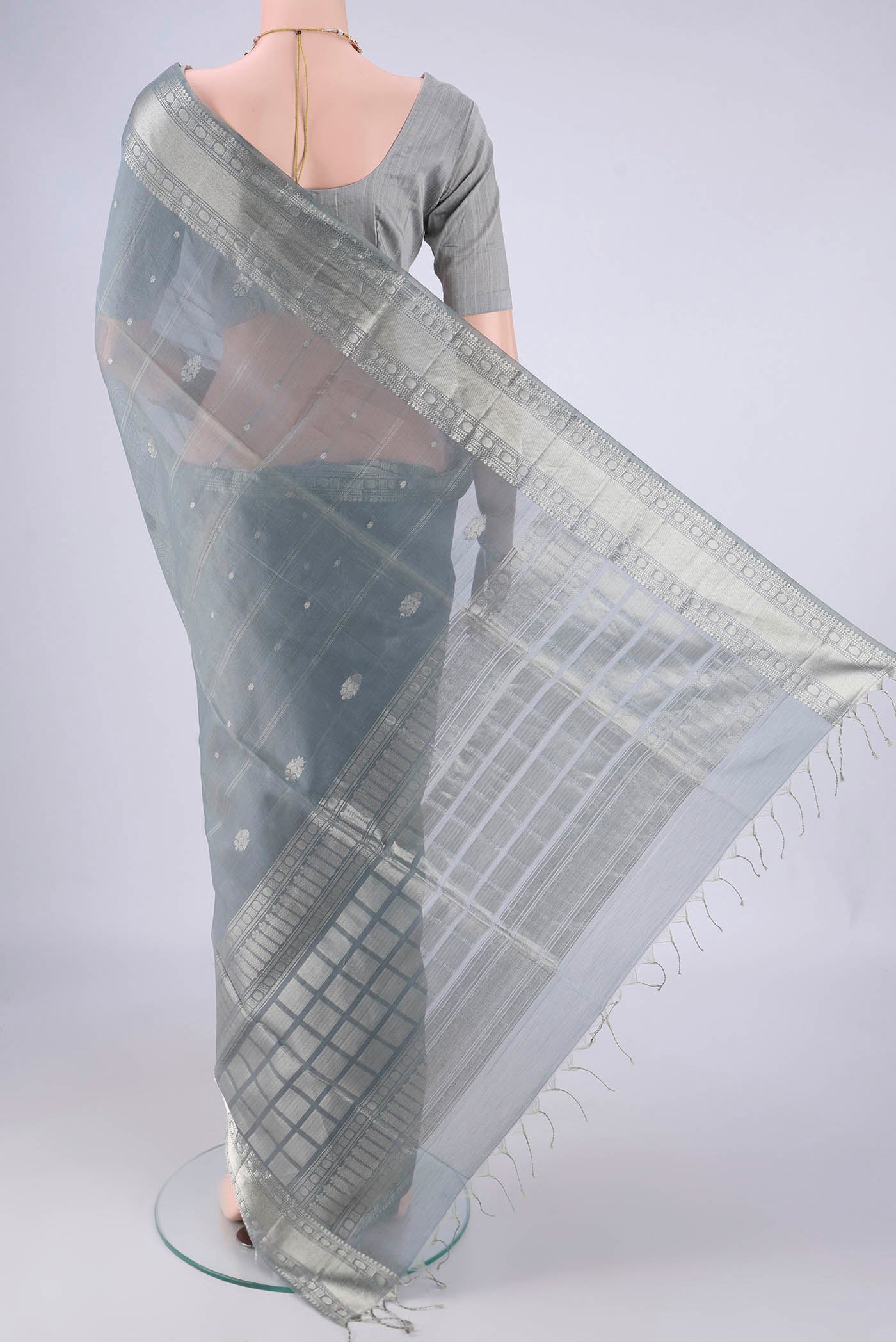 Flat view of Grey Silk Cotton Saree with Zari Butta on the body and Zari Border. 