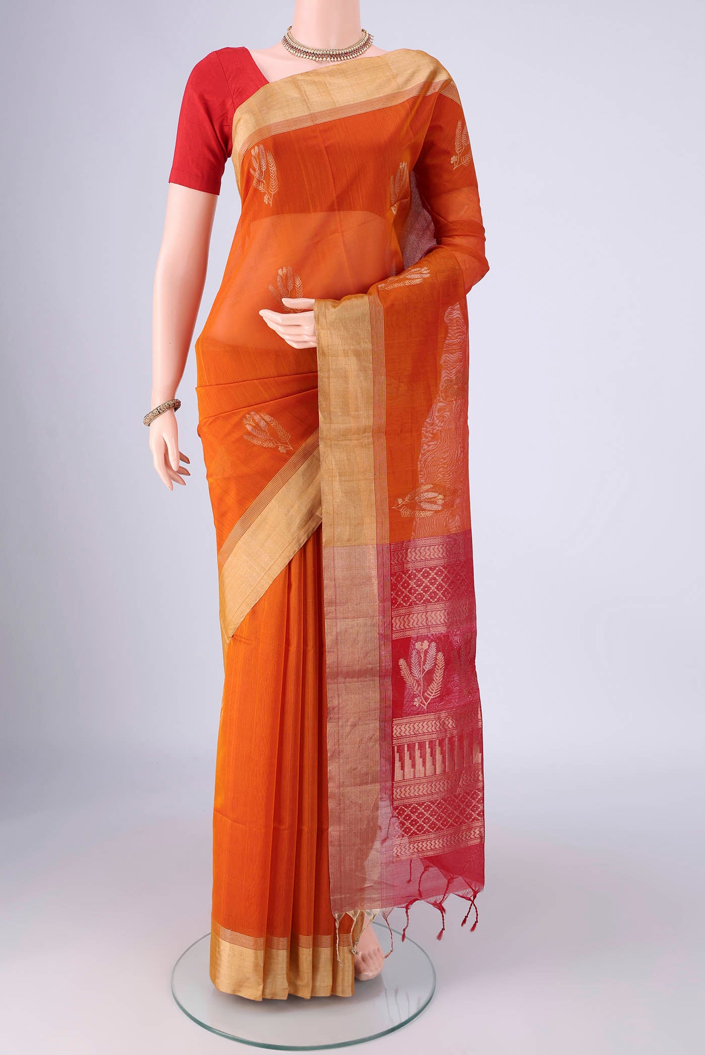 Brick Orange Silk Cotton Saree with Zari Butta on the body and Zari Border.  displayed on a mannequin