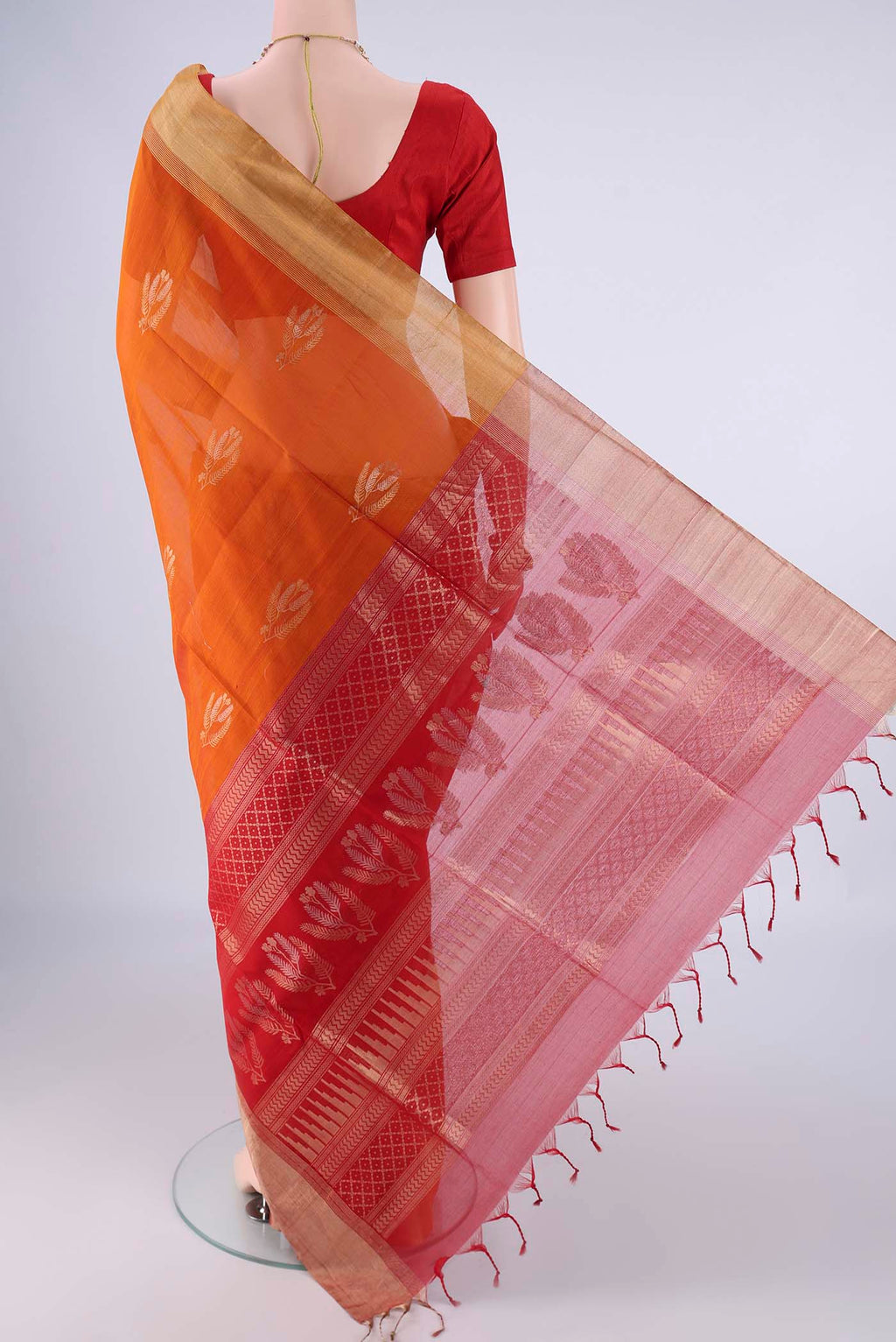 Flat view of Brick Orange Silk Cotton Saree with Zari Butta on the body and Zari Border. 