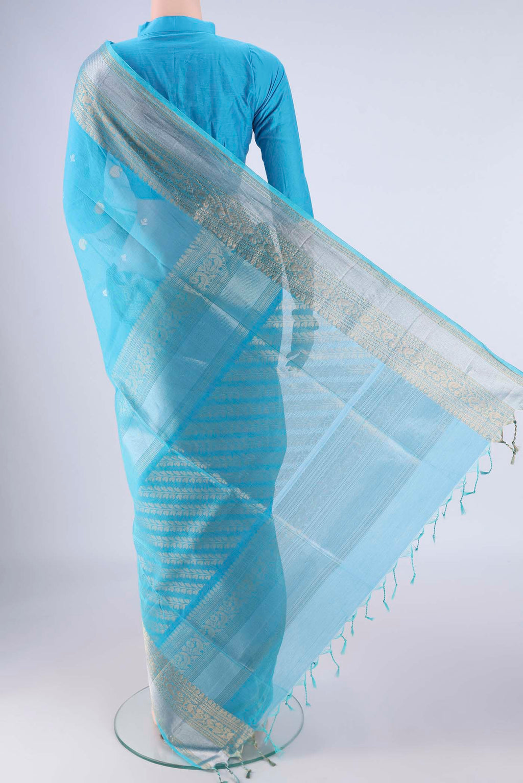 Flat view of Sky Blue Silk Cotton Saree with Zari Butta on the body and Zari Border. 