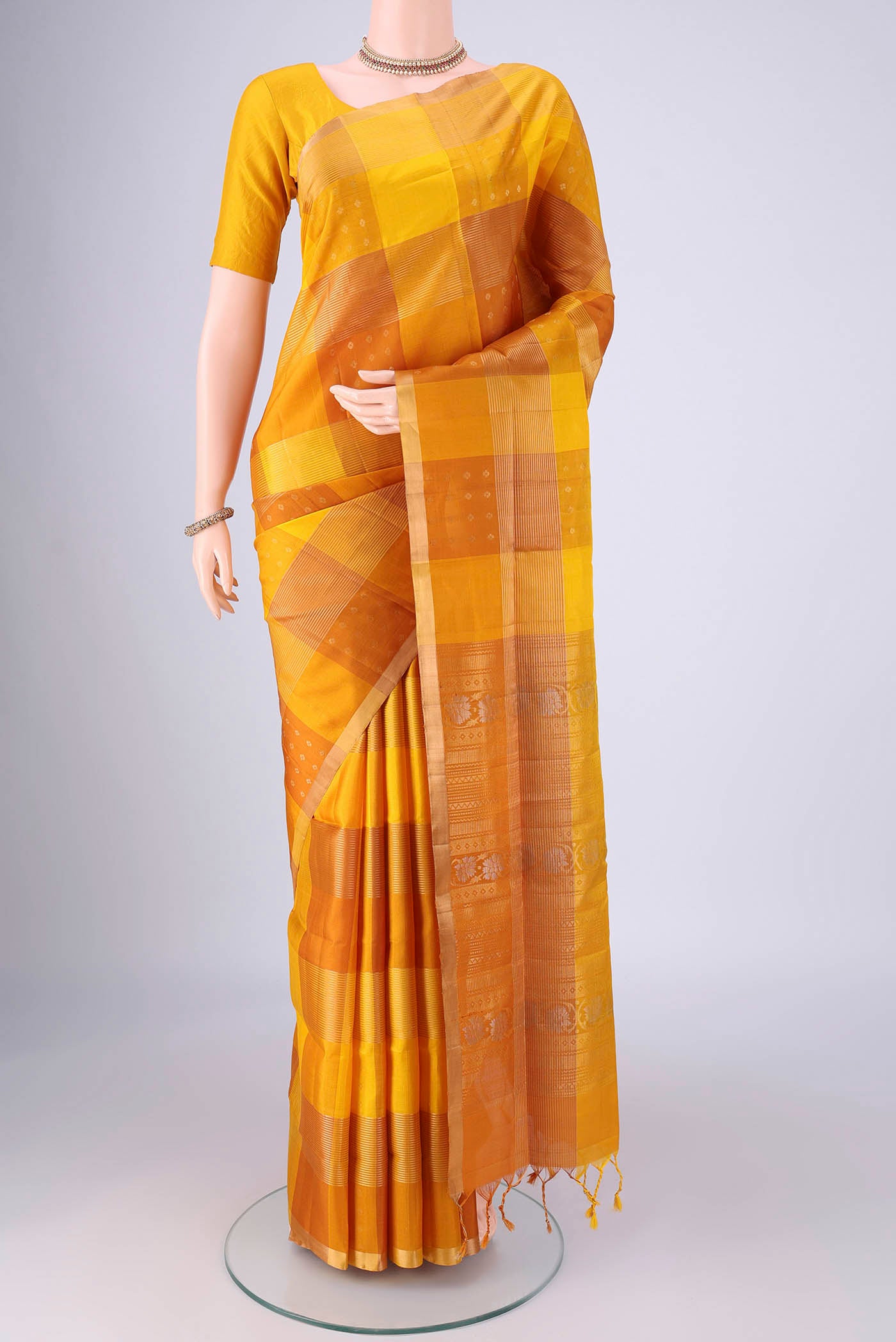 Mustard Soft Silk Saree with Checked design on the body and Zari Border.  displayed on a mannequin