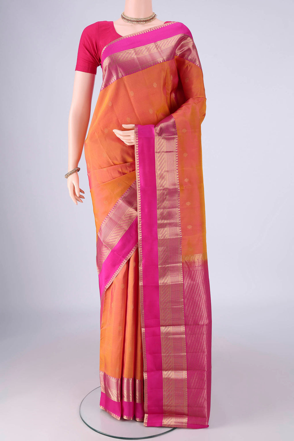 Pinkish Yellow Dual Tone Kanchipuram Silk Saree with Zari Butta on the body and Zari Border.  displayed on a mannequin