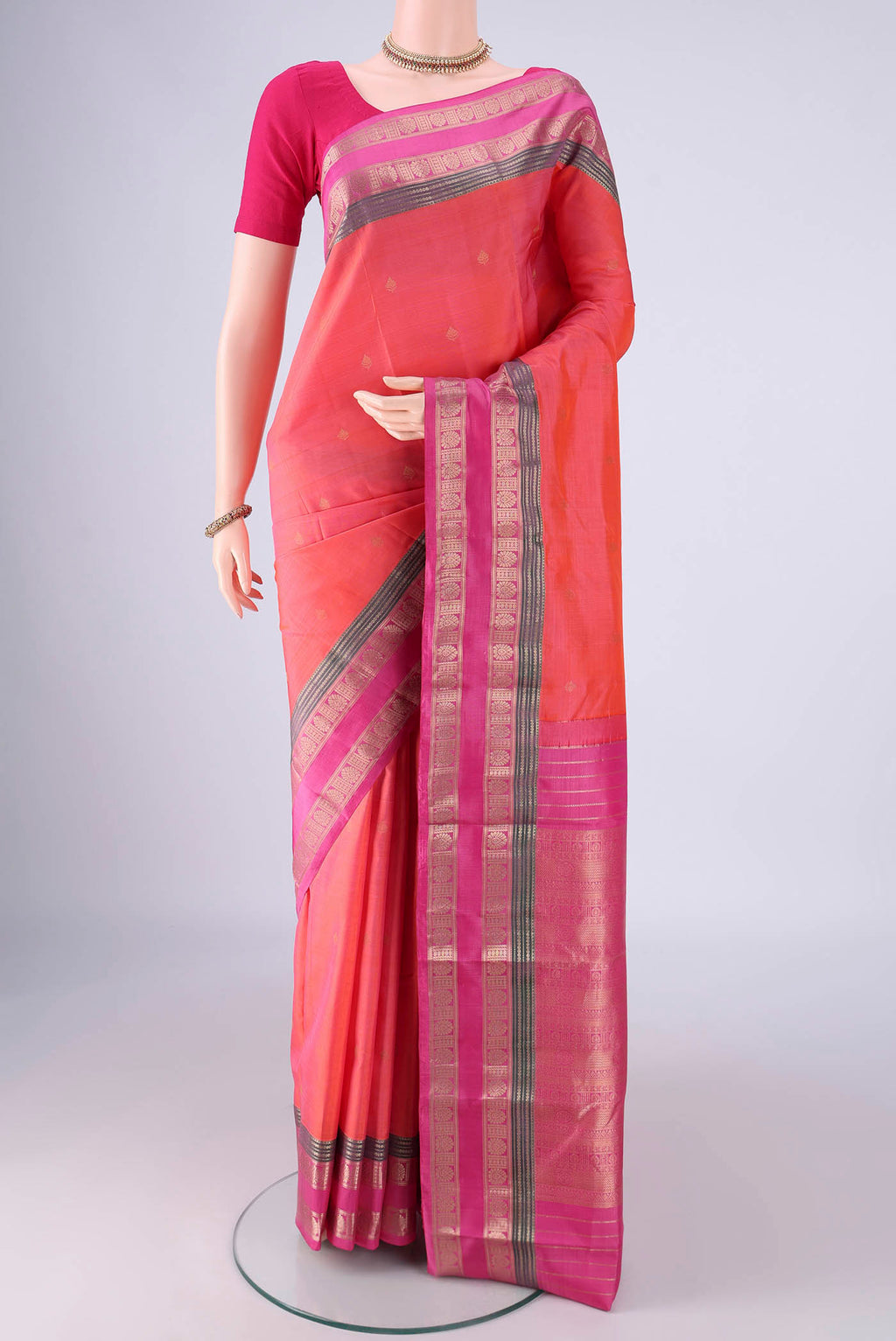 Coral Kanchipuram Silk Saree with Zari Butta on the body and Zari Border.  displayed on a mannequin