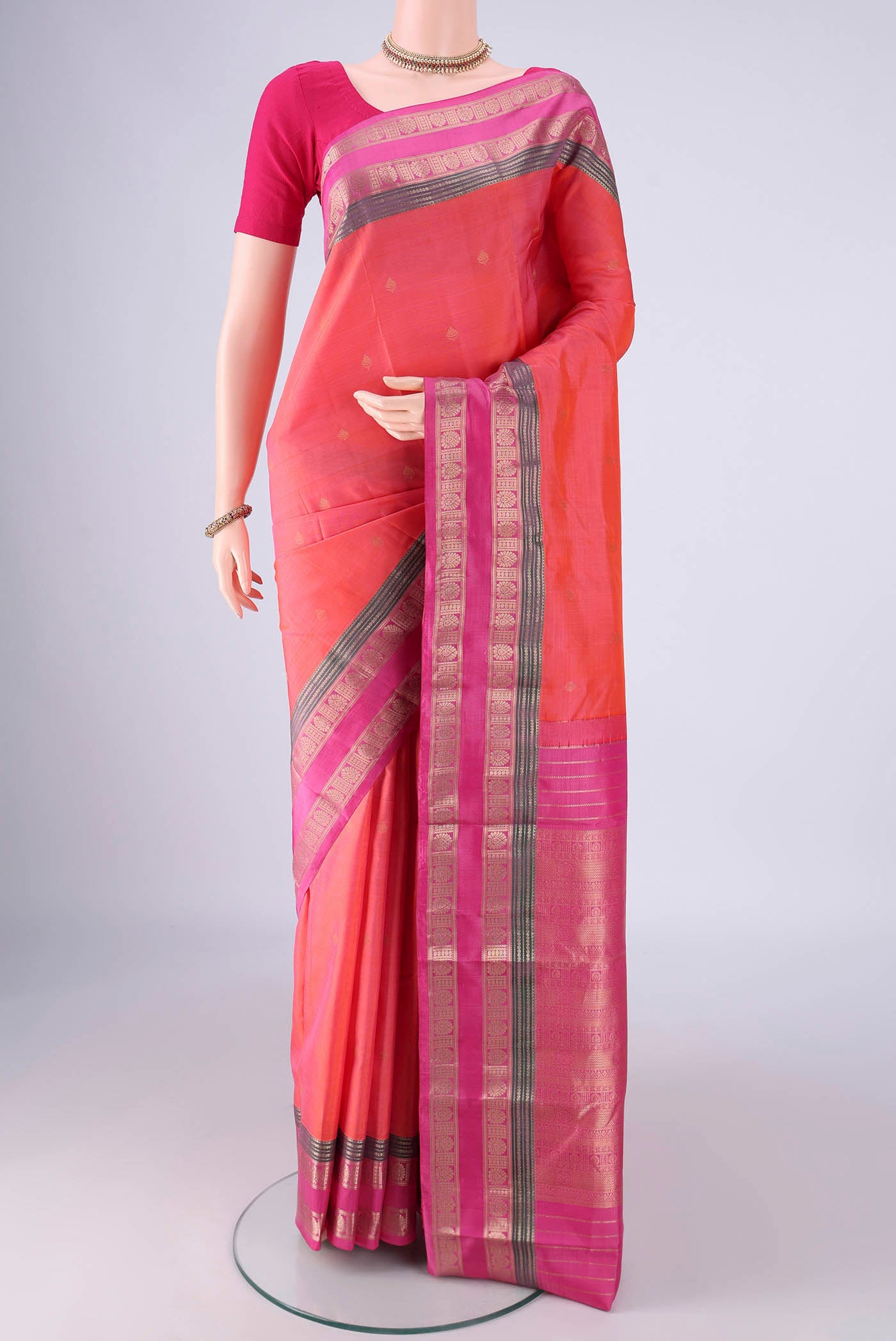 Coral Kanchipuram Silk Saree with Zari Butta on the body and Zari Border.  displayed on a mannequin