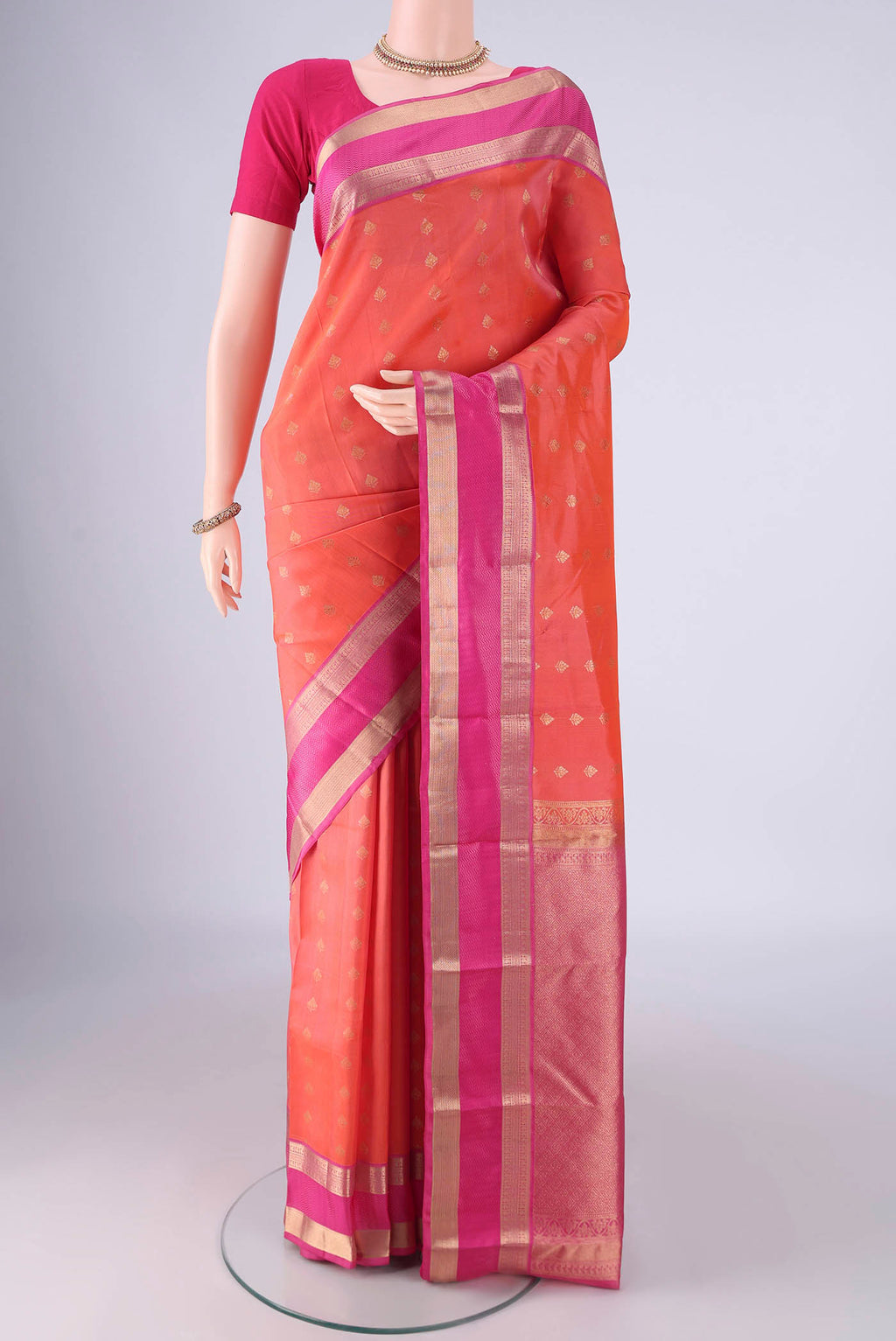 Orange Kanchipuram Silk Saree with Zari Butta on the body and Zari Border.  displayed on a mannequin