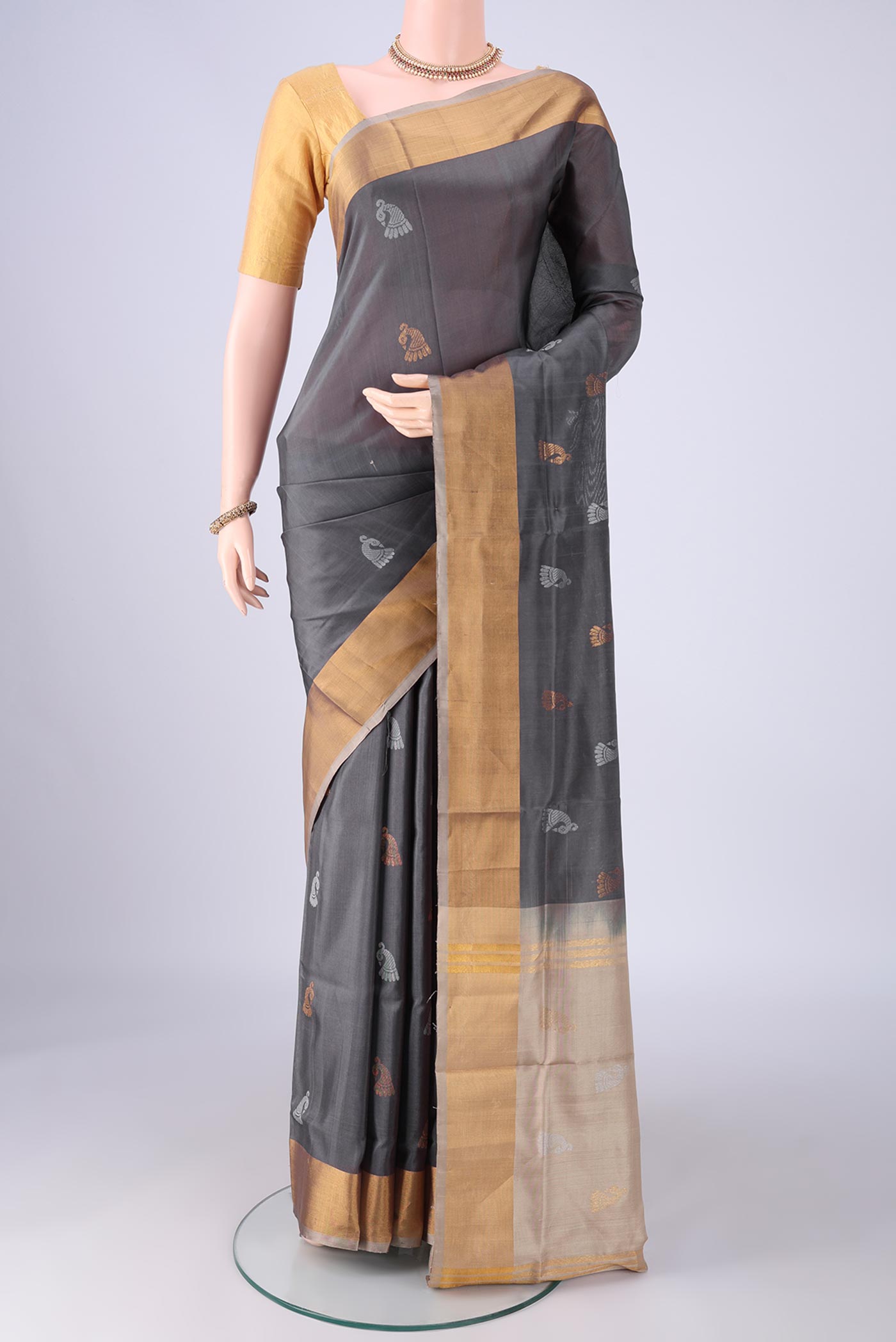 Grey Uppada Silk Saree with Zari And Thread Butta on the body and Zari Border.  displayed on a mannequin