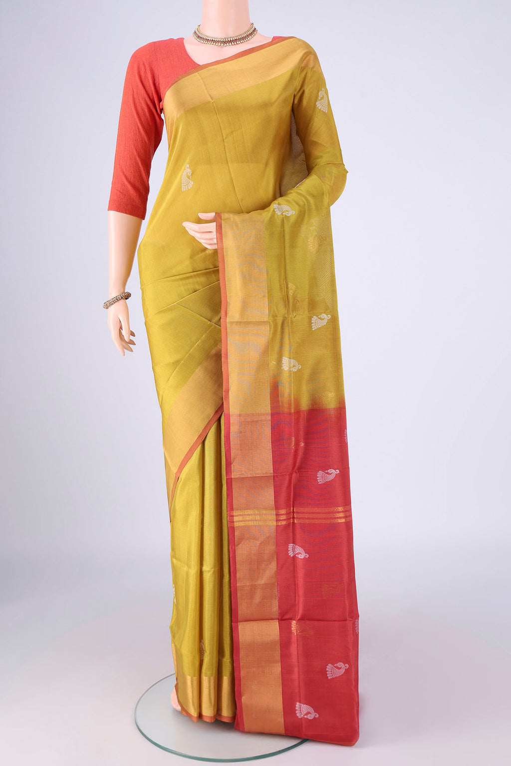 Mustard Uppada Silk Saree with Zari And Thread Butta on the body and Zari Border.  displayed on a mannequin
