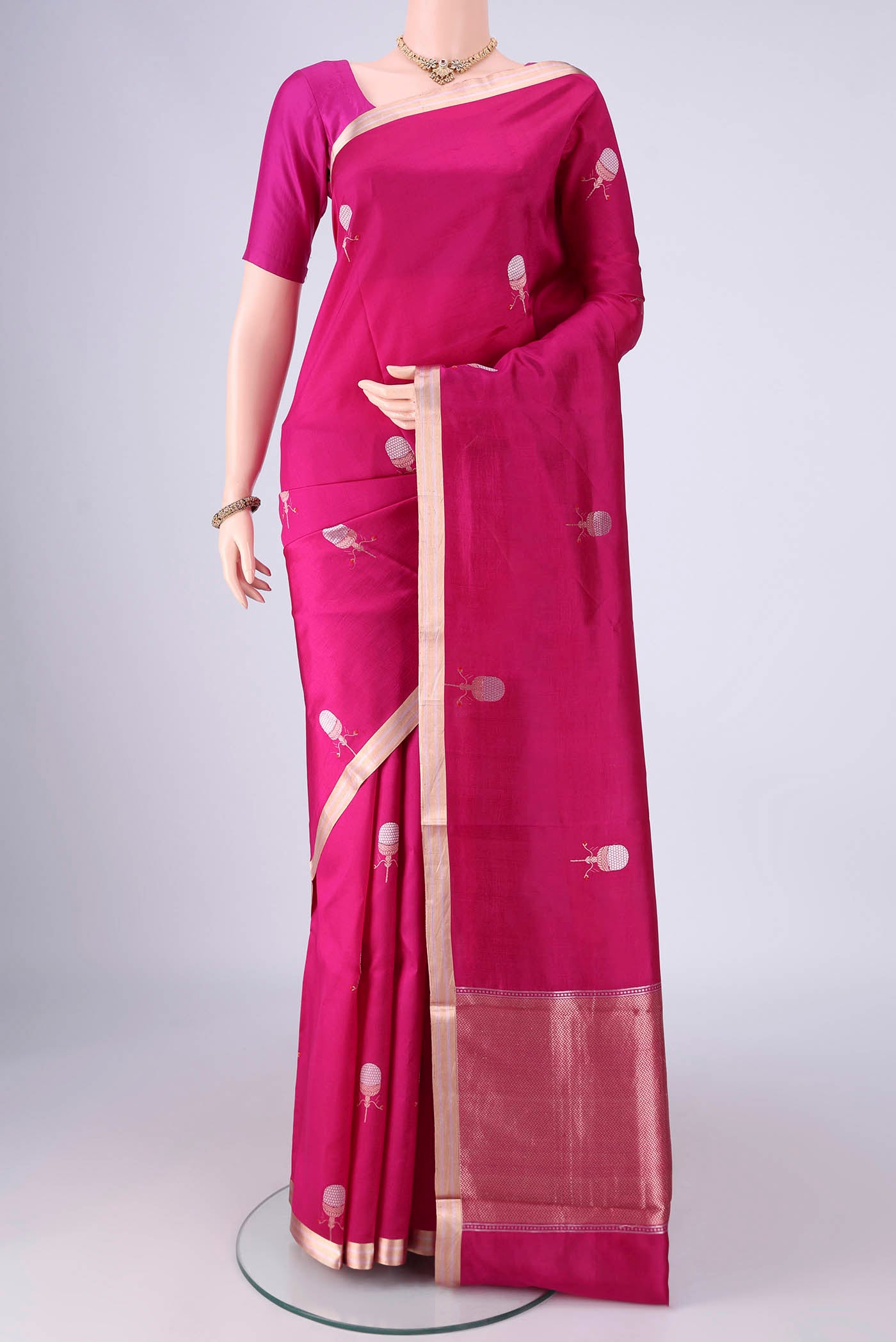 Rani Pink Banarasi Silk Saree with Zari And Thread Butta on the body and Zari Border.  displayed on a mannequin