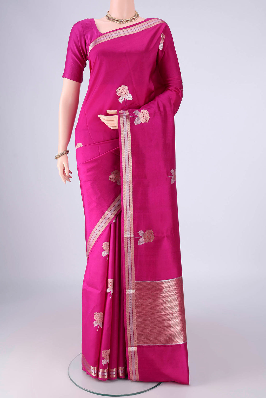 Rani Pink Banarasi Silk Saree with Zari And Thread Butta on the body and Zari Border.  displayed on a mannequin