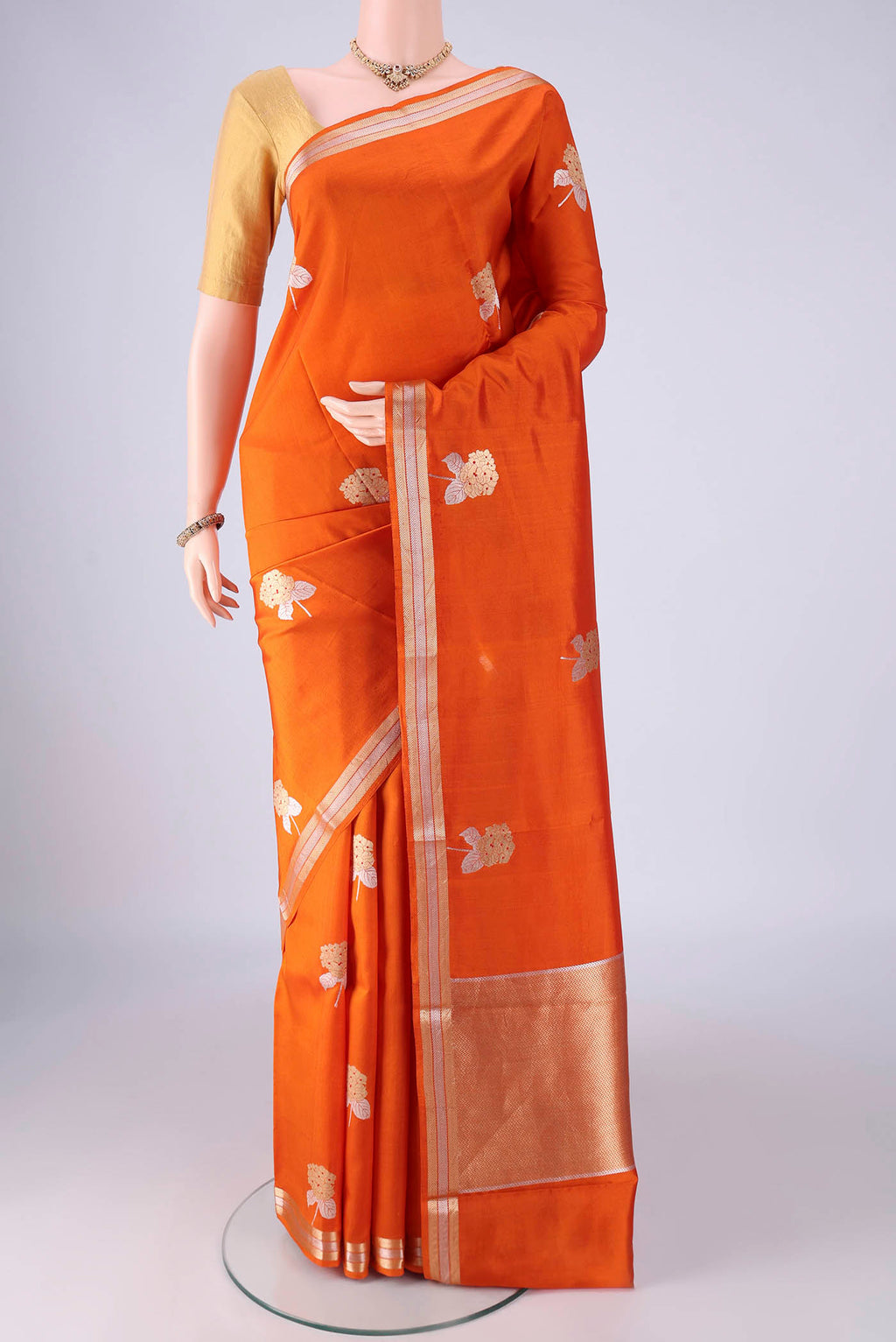 Rust Banarasi Silk Saree with Zari Butta on the body and Zari Border.  displayed on a mannequin