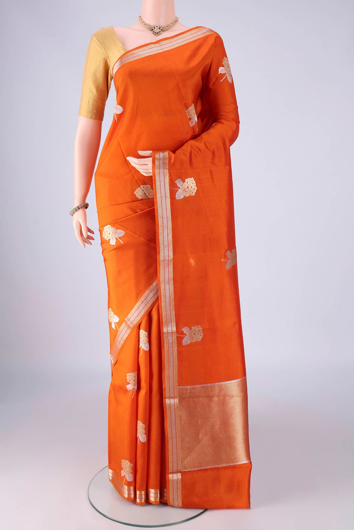 Rust Banarasi Silk Saree with Zari Butta on the body and Zari Border.  displayed on a mannequin