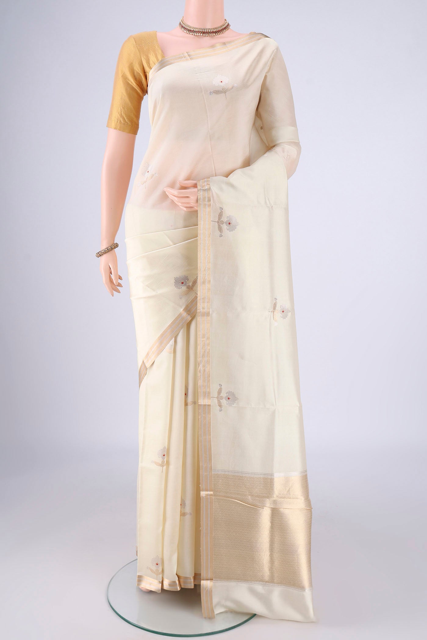 Cream Banarasi Silk Saree with Zari Butta on the body and Zari Border.  displayed on a mannequin