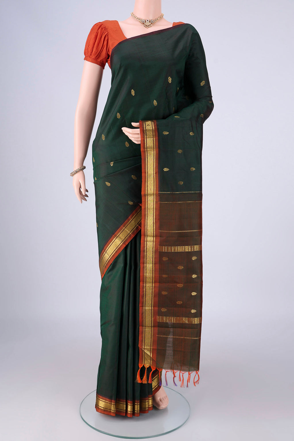 Bottle Green Kanchipuram Silk Saree with Zari Butta on the body and One Side Border.  displayed on a mannequin