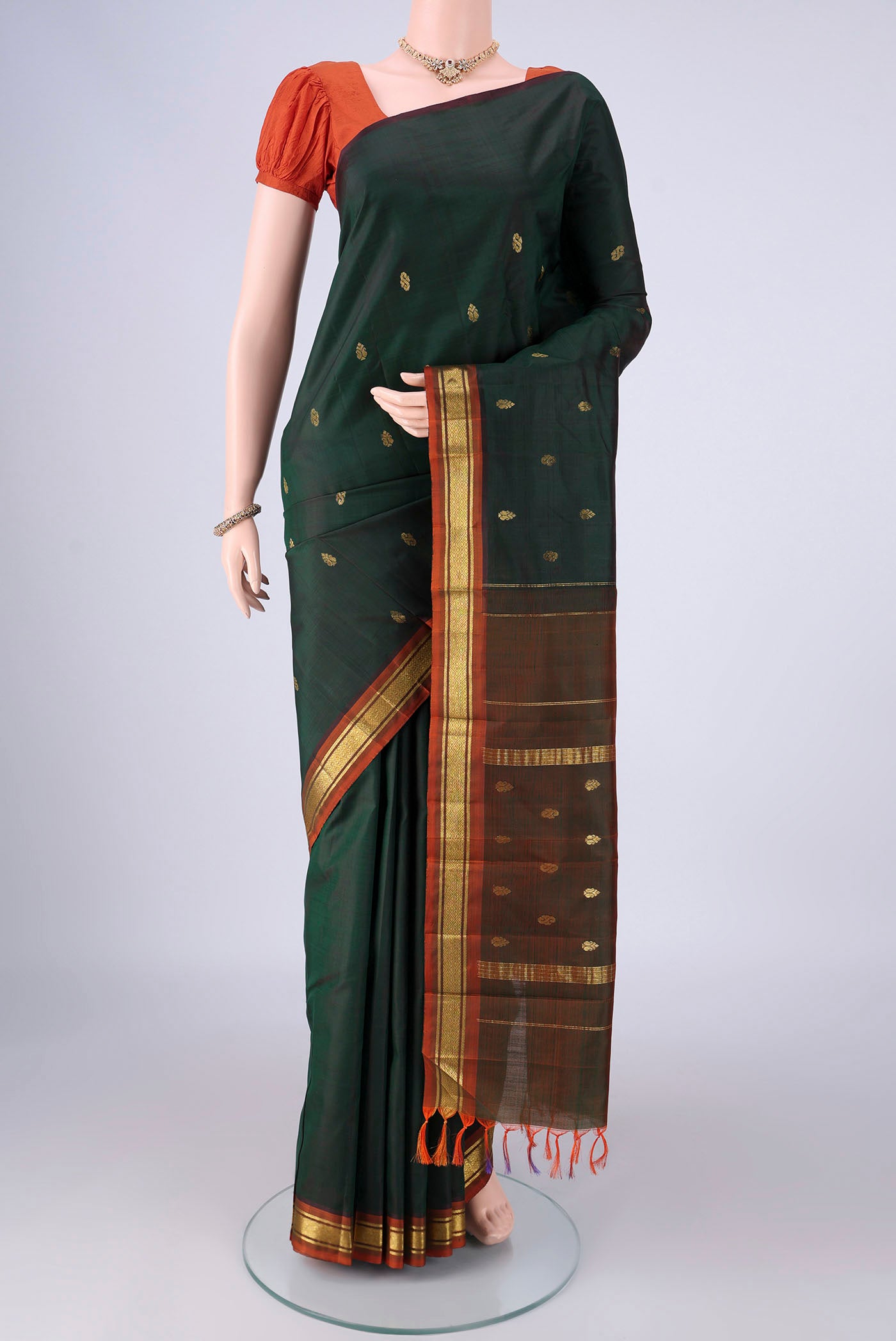 Bottle Green Kanchipuram Silk Saree with Zari Butta on the body and One Side Border.  displayed on a mannequin