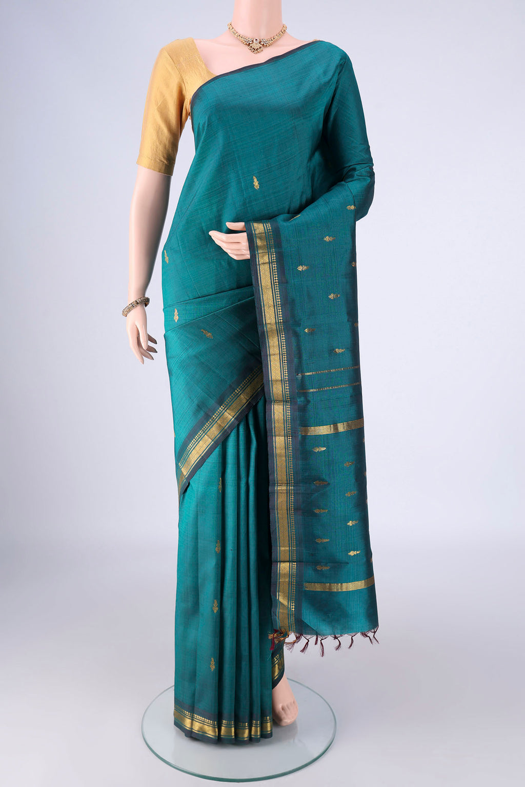 Green Kanchipuram Silk Saree with Zari Butta on the body and One Side Border.  displayed on a mannequin