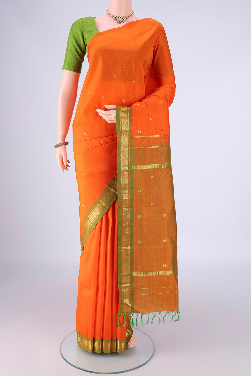Orange Kanchipuram Silk Saree with Zari Butta on the body and One Side Border.  displayed on a mannequin