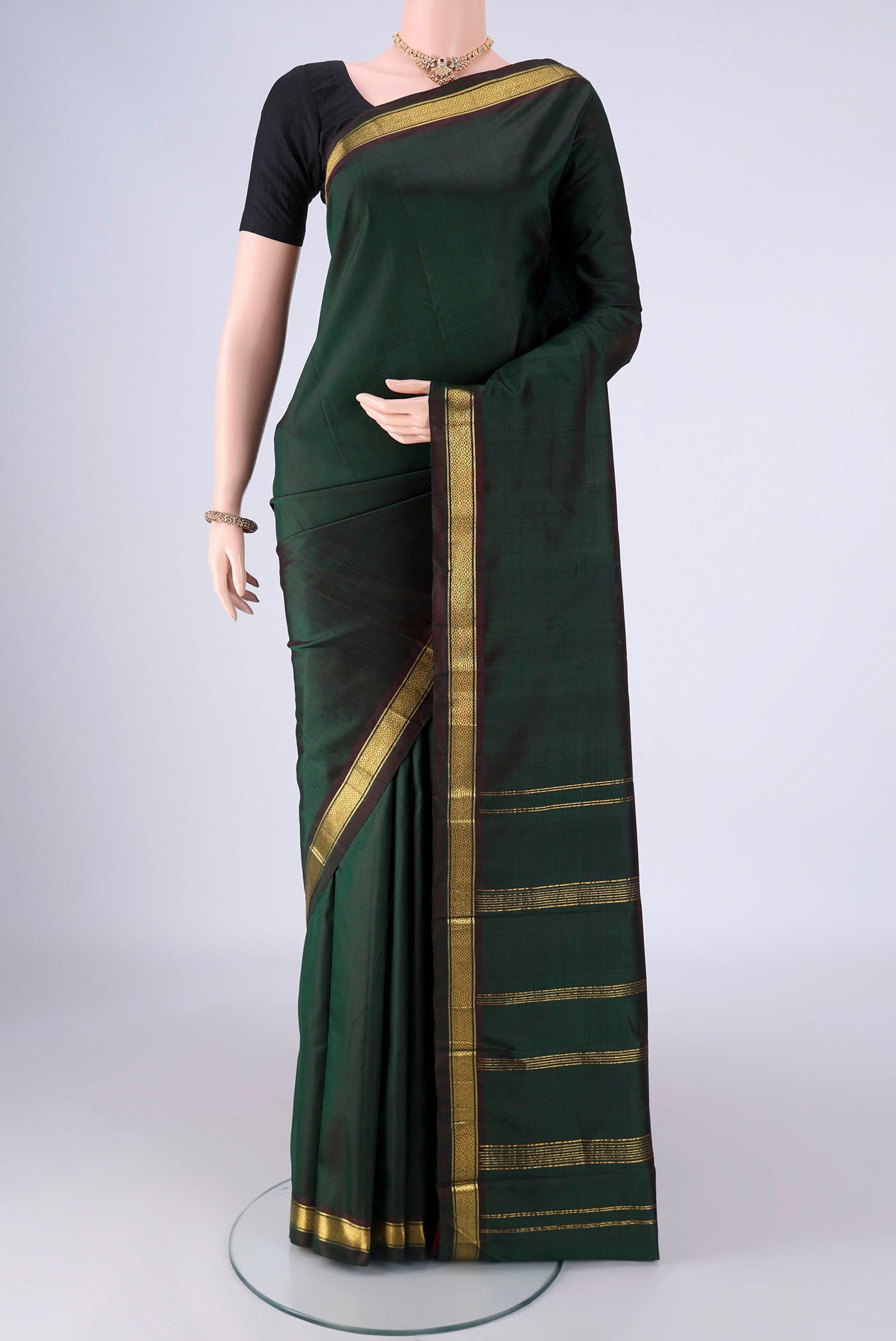Bottle Green Kanjivaram Silk Saree with Plain Body and Zari Border.  displayed on a mannequin