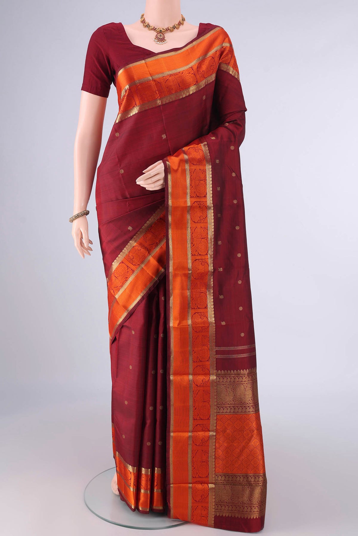 Pure Silk Pure Zari Maroon Kanchipuram Saree with Zari Butta on the body and Zari And Thread Border.  displayed on a mannequin