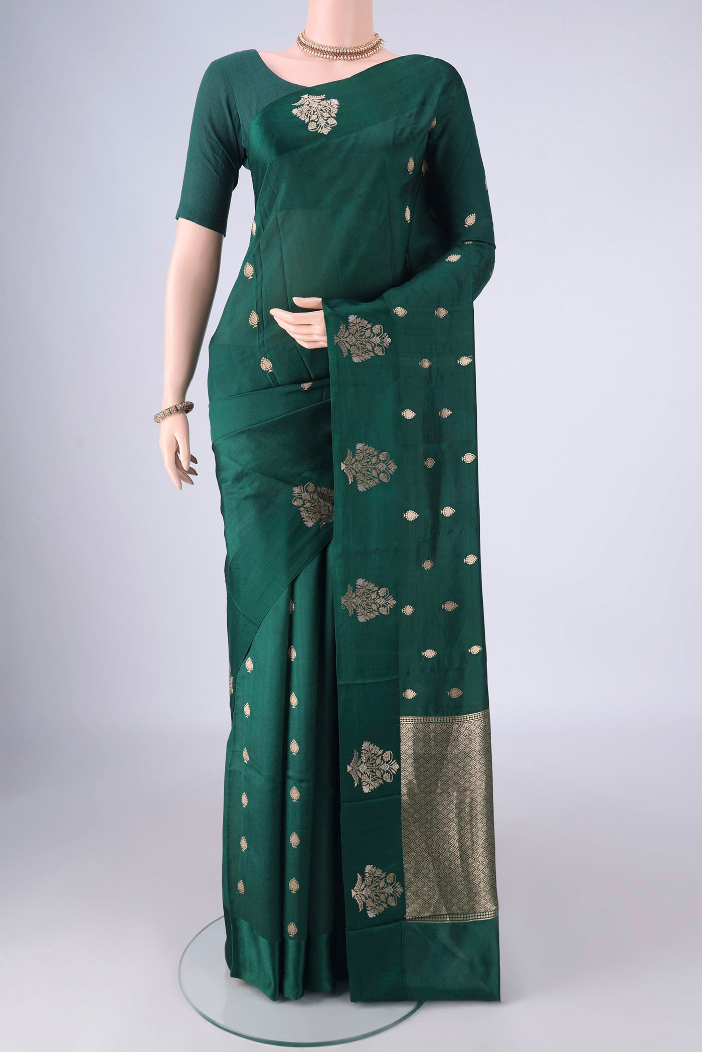 Bottle Green Banarasi Katan Silk Saree with Zari Butta on the body and Satin Border.  displayed on a mannequin