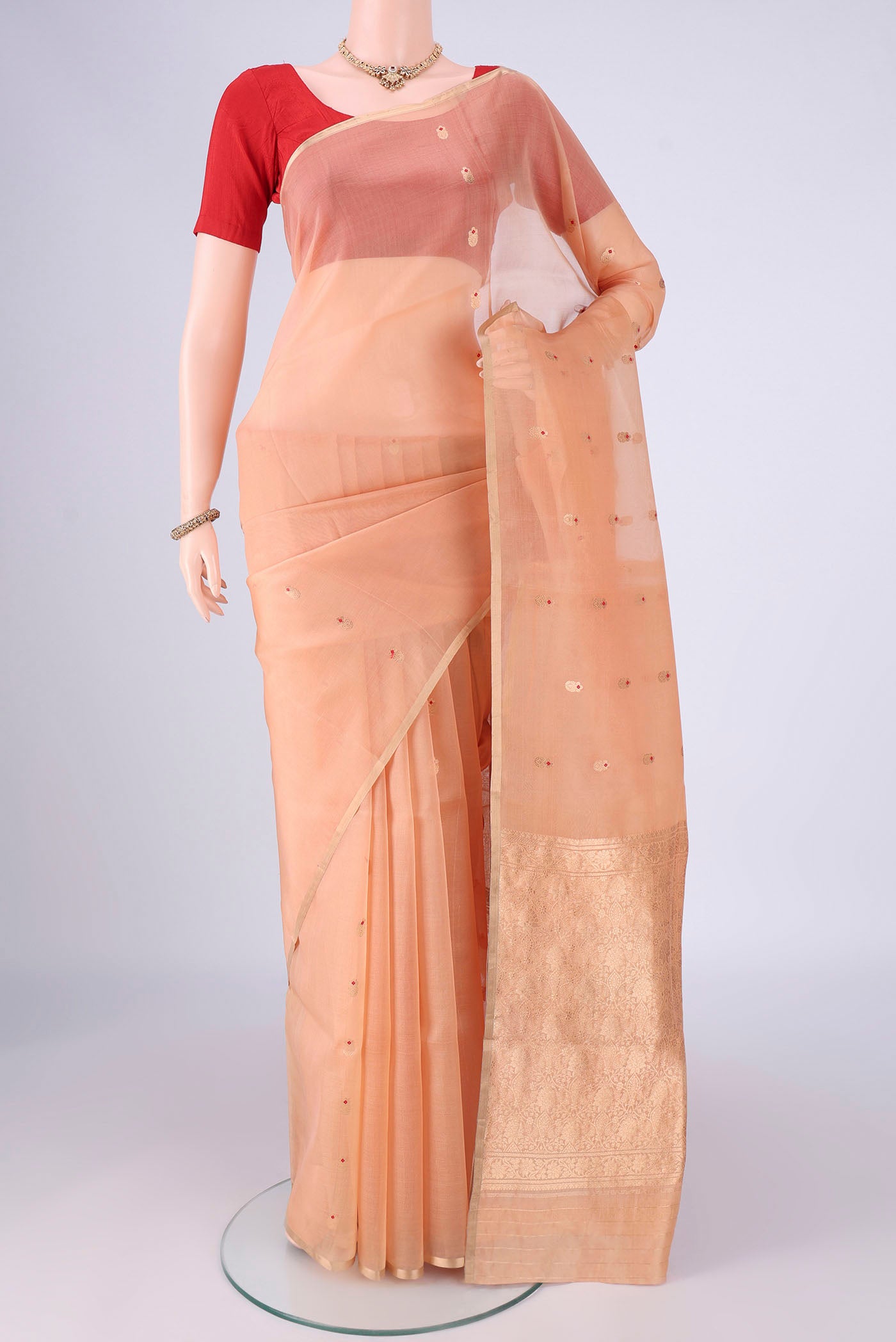 Peach Organza Silk Saree with Zari And Thread Butta on the body and Thin Zari Line.  displayed on a mannequin