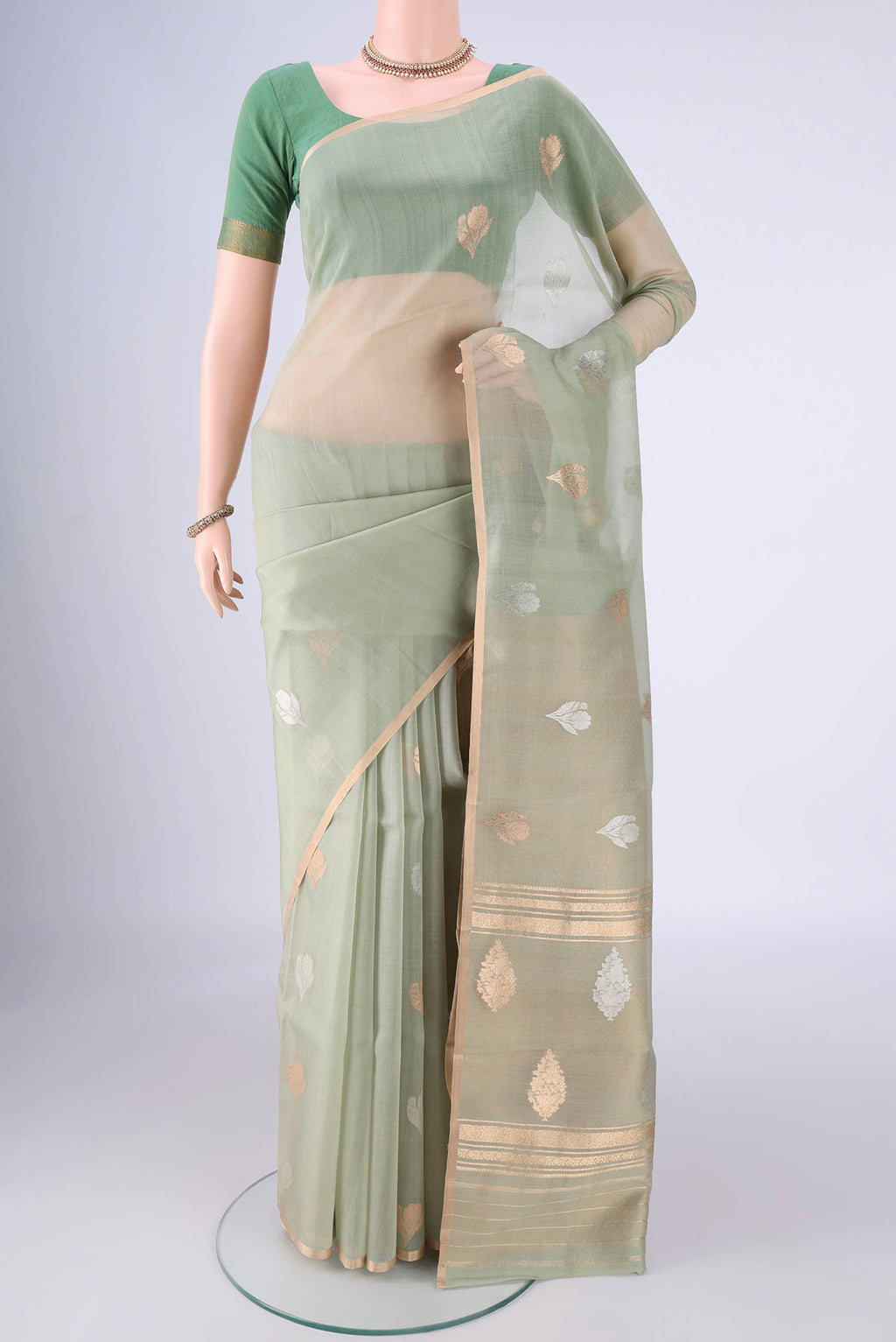 Pista Green Organza Silk Saree with Zari Butta on the body and Thin Zari Line.  displayed on a mannequin