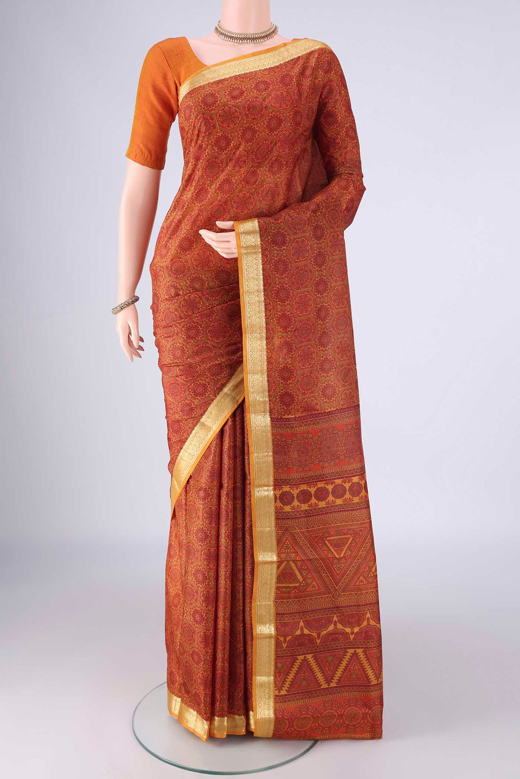 Rust Printed Silk Saree with Printed design on the body and Zari Border.  displayed on a mannequin