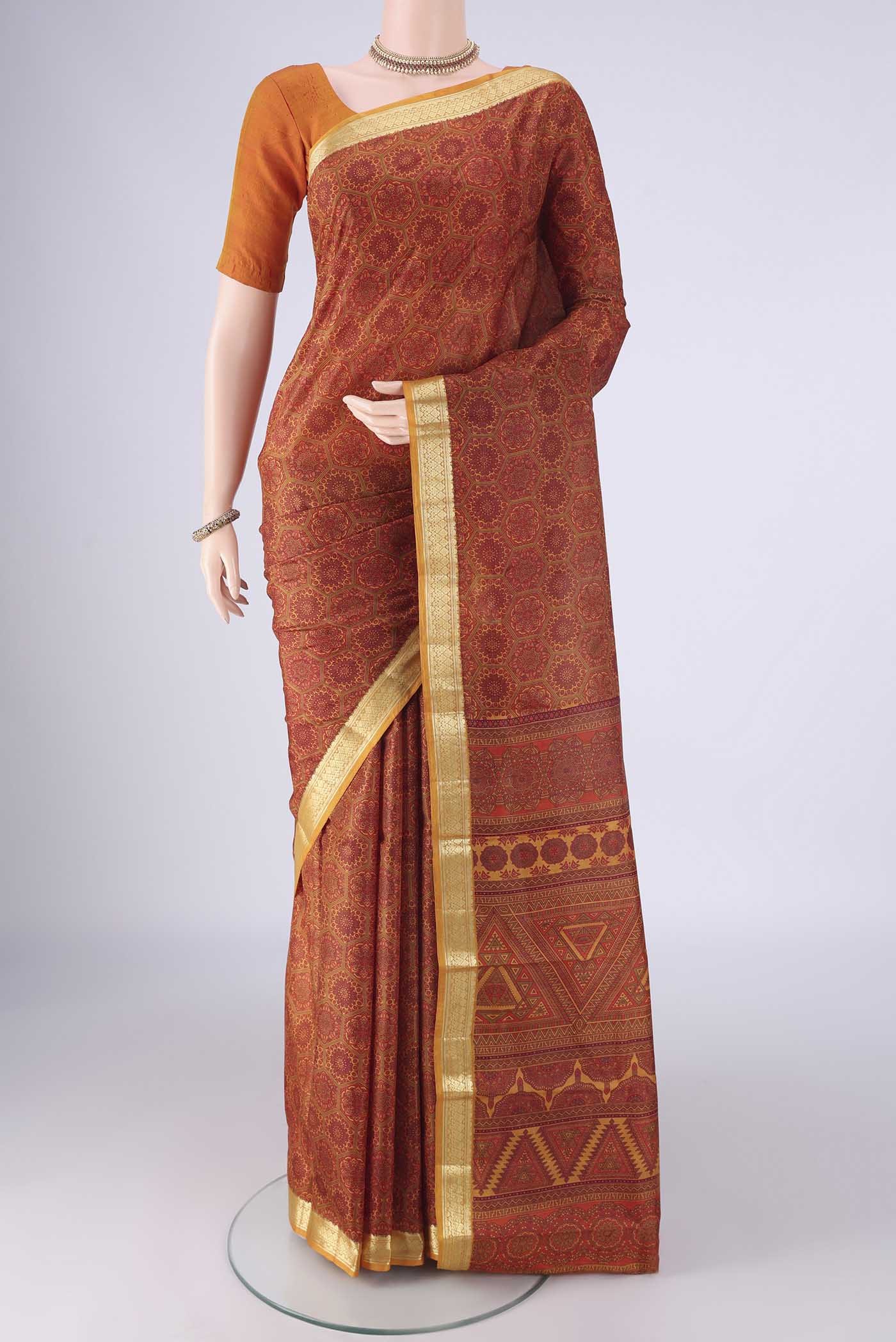 Rust Printed Silk Saree with Printed design on the body and Zari Border.  displayed on a mannequin