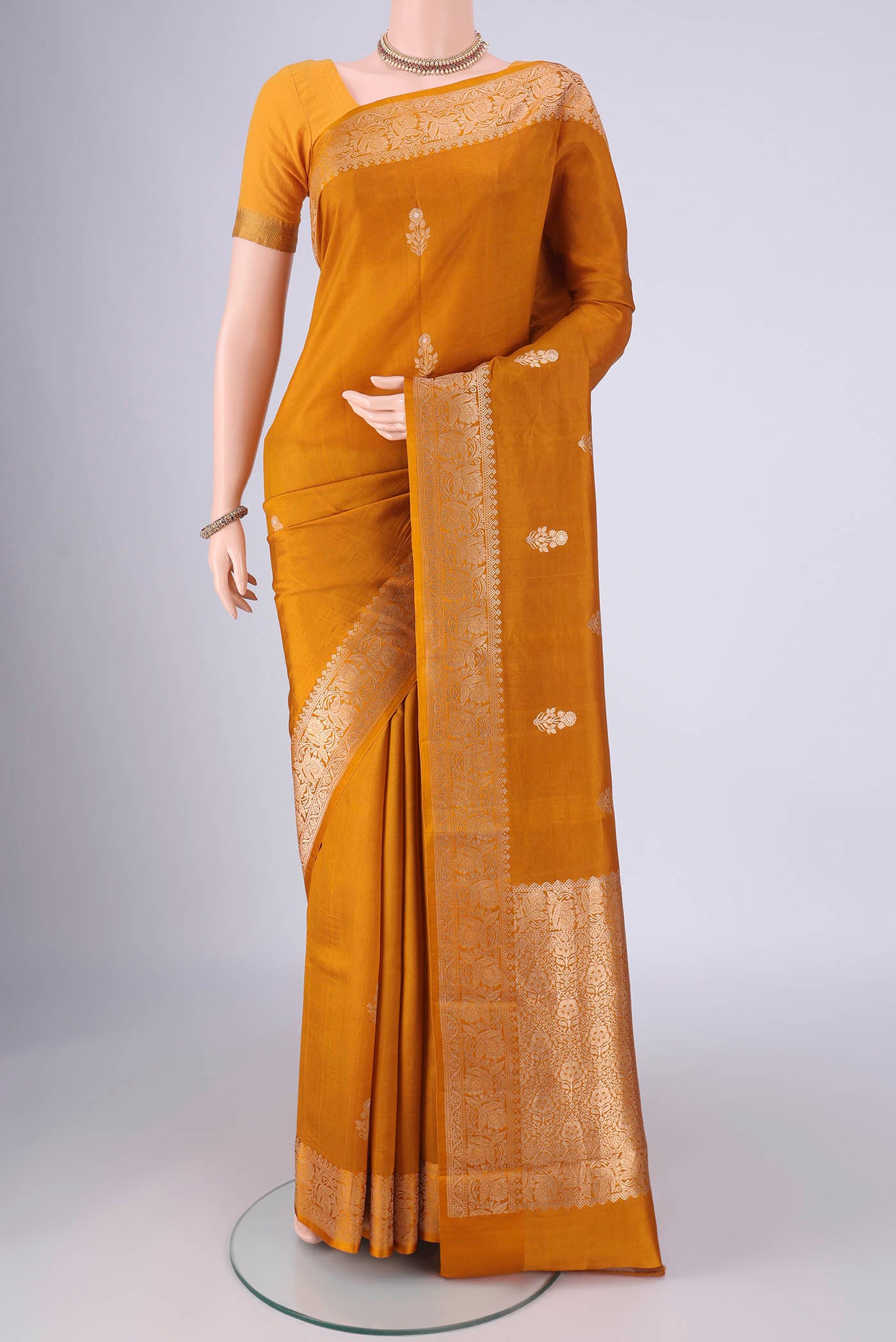 Mustard Banarasi Katan Silk Saree with Zari Butta on the body and Zari Border.  displayed on a mannequin