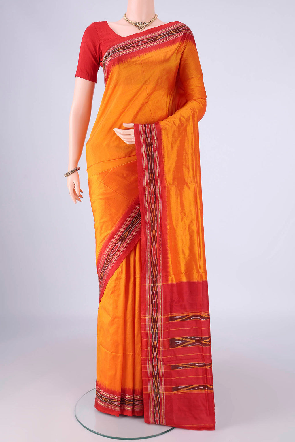 Orange Pochampally Silk Saree with Plain Body and Ikat Border.  displayed on a mannequin