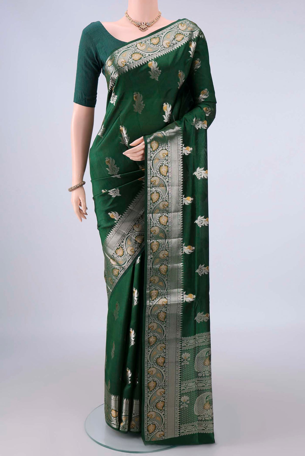 Pure Silk Bottle Green Banarasi Raw Saree with Zari Butta on the body and Zari Border.  displayed on a mannequin