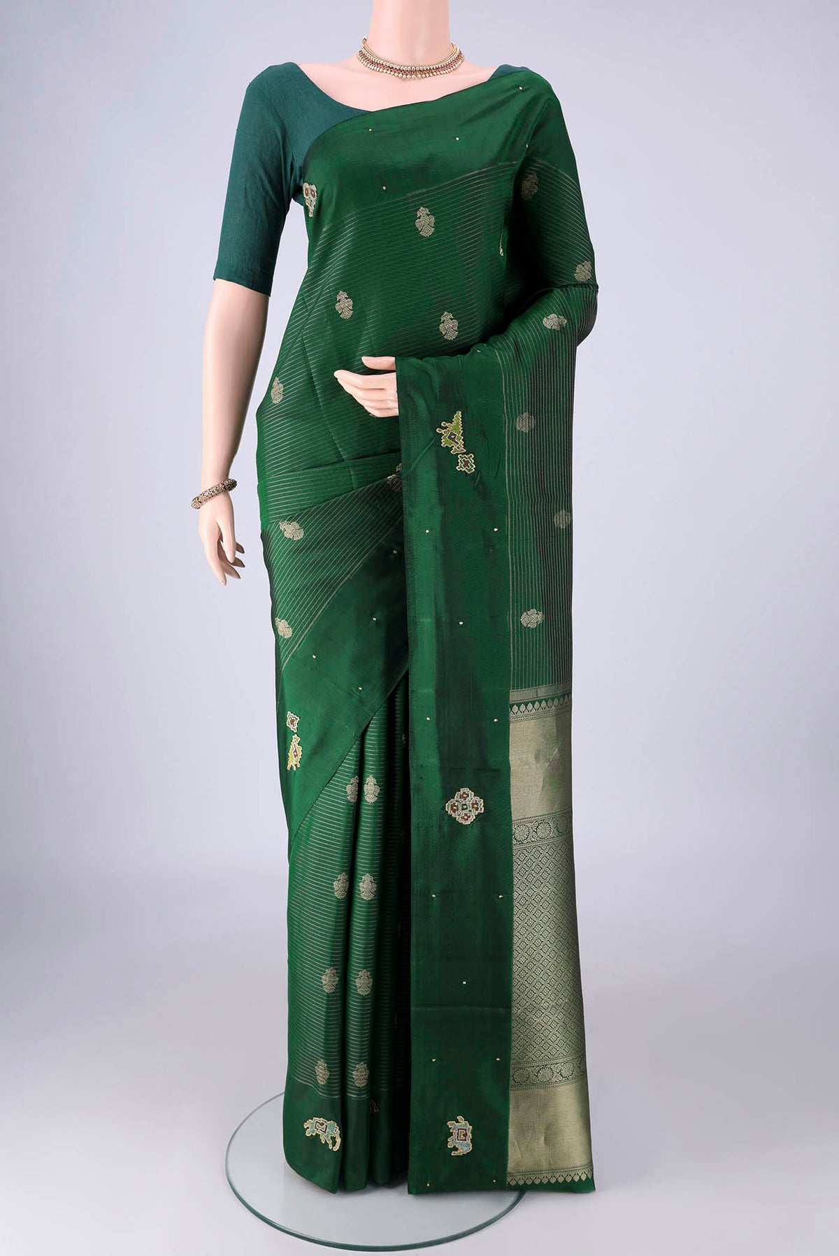 Green Kanchipuram Silk Saree with Zari Butta on the body and Zari Border.  displayed on a mannequin