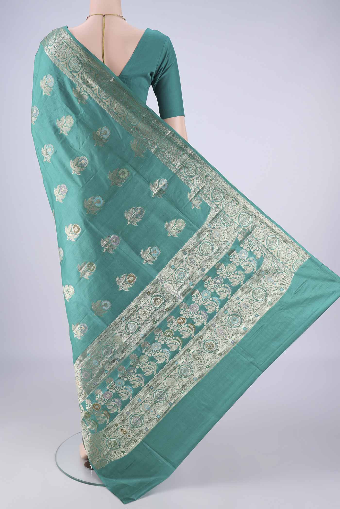 Flat view of Turquoise Banarasi Tussar Silk Saree with Zari And Thread Butta on the body and Zari Border. 