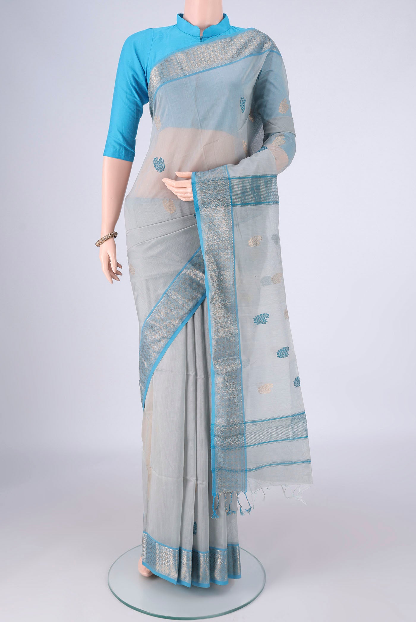 Blue Grey Maheshwari Silk Cotton Saree with Zari And Thread Butta on the body and Zari Border.  displayed on a mannequin