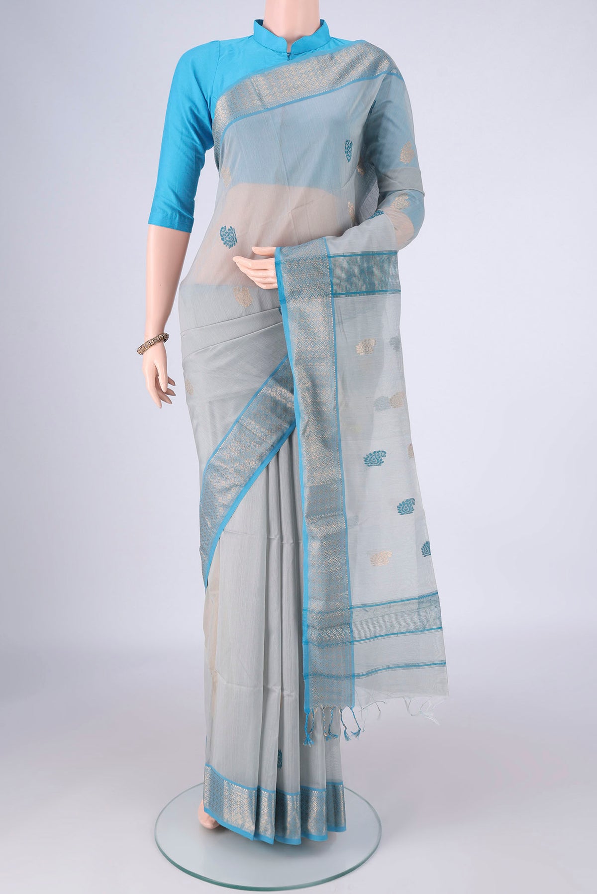 Blue Grey Maheshwari Silk Cotton Saree with Zari And Thread Butta on the body and Zari Border.  displayed on a mannequin