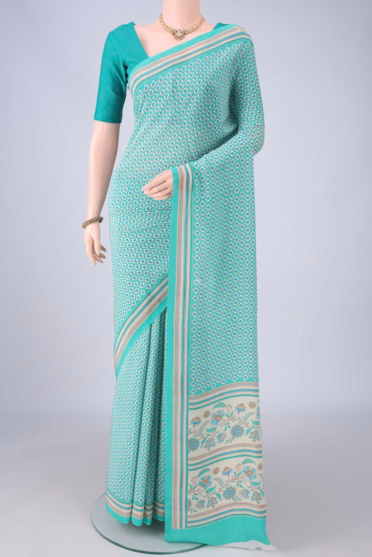 Turquoise Mysore Crepe Saree with Floral Print on the body and Plain Border.  displayed on a mannequin