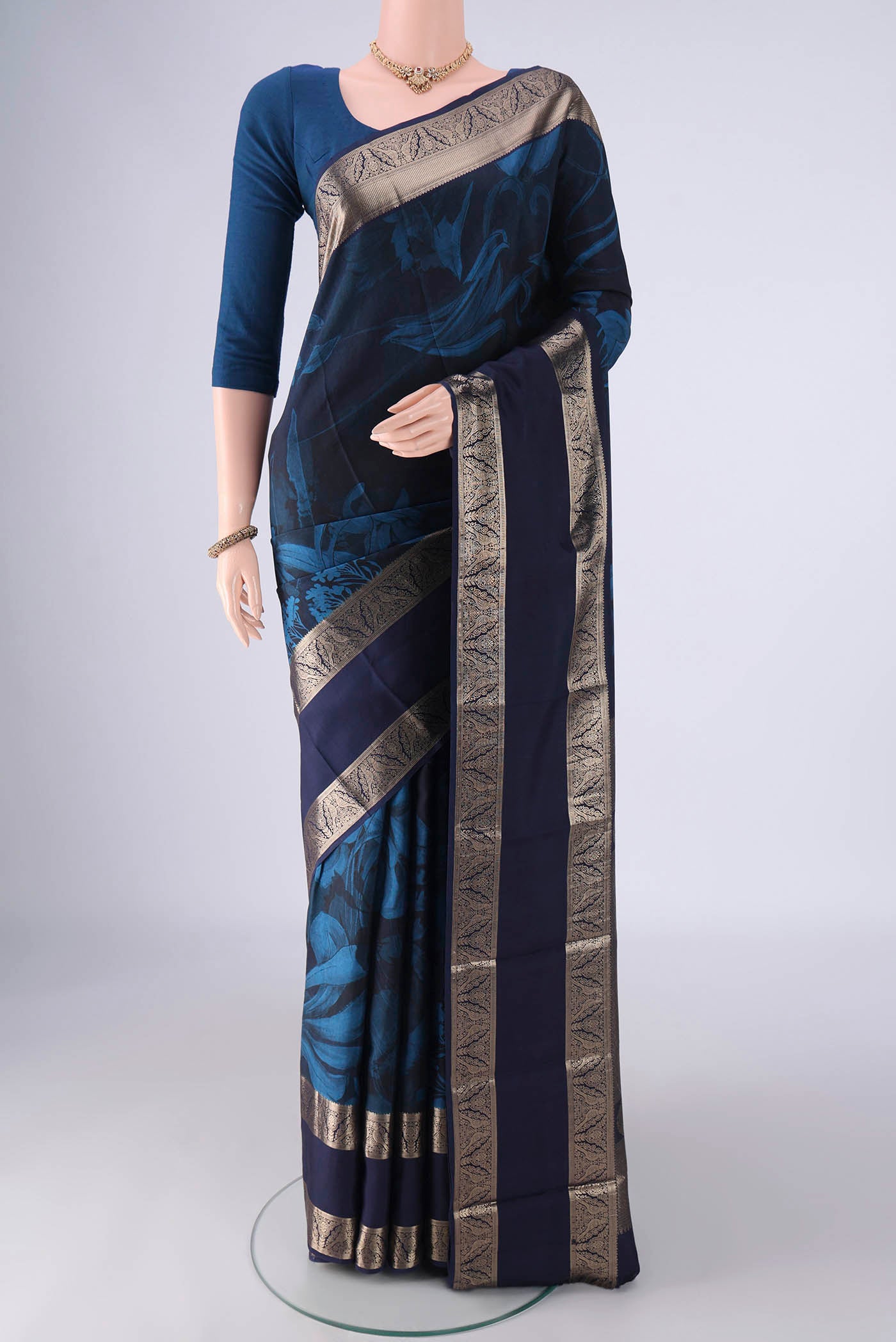 Navy Blue Kanchipuram Silk Saree with Floral Print on the body and Zari Border.  displayed on a mannequin