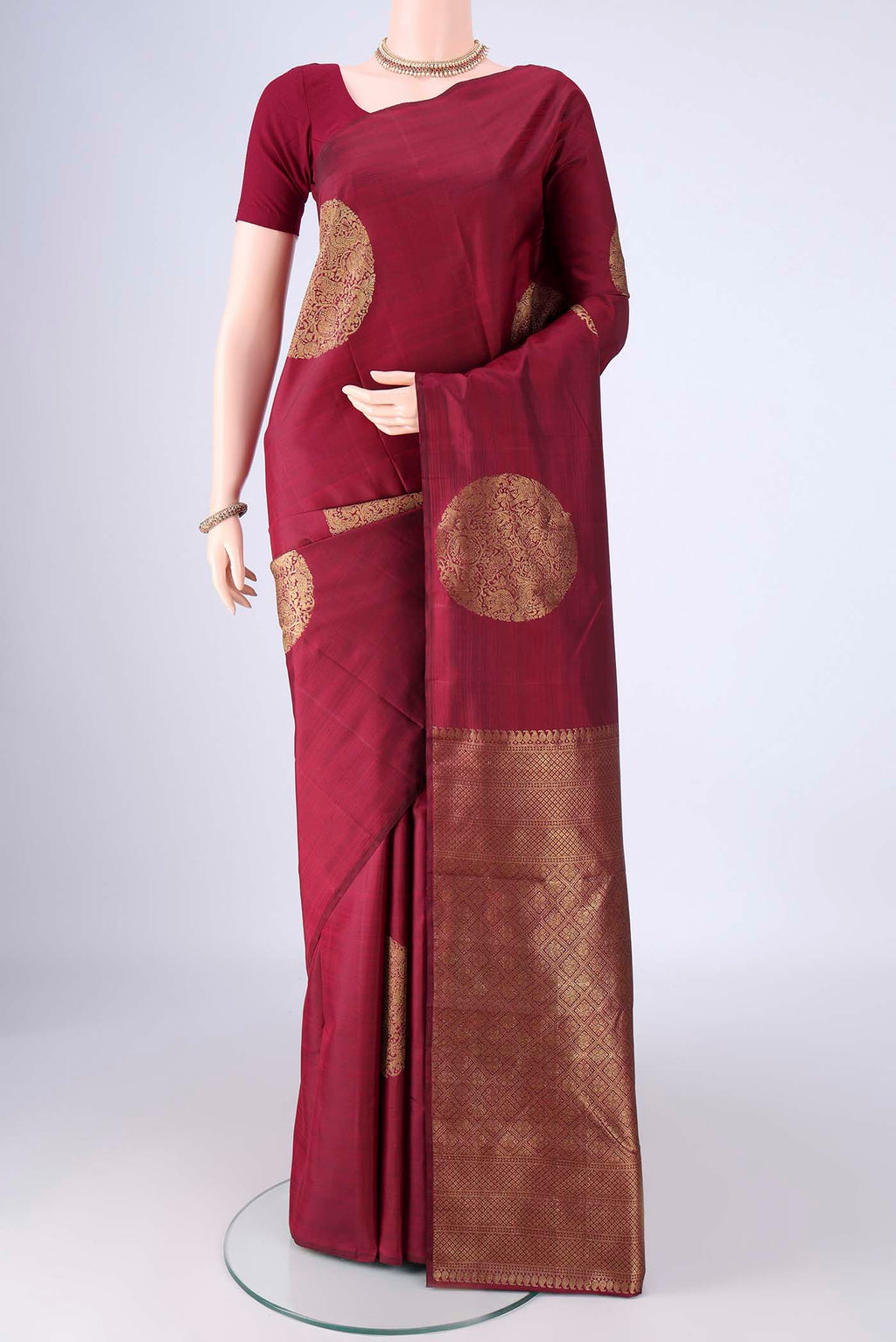 Maroon Kanchipuram Silk Saree with Zari Butta on the body and Without Border.  displayed on a mannequin