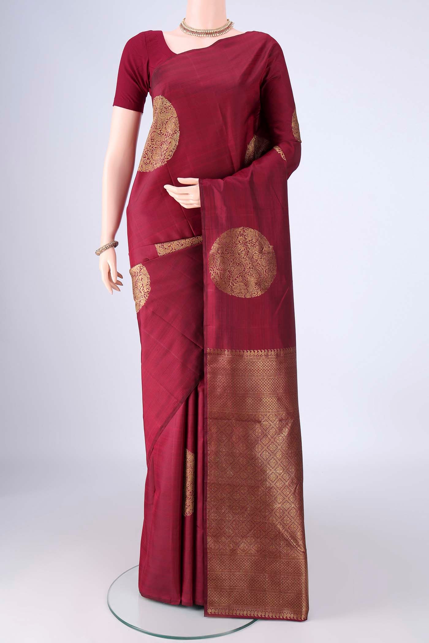 Maroon Kanchipuram Silk Saree with Zari Butta on the body and Without Border.  displayed on a mannequin