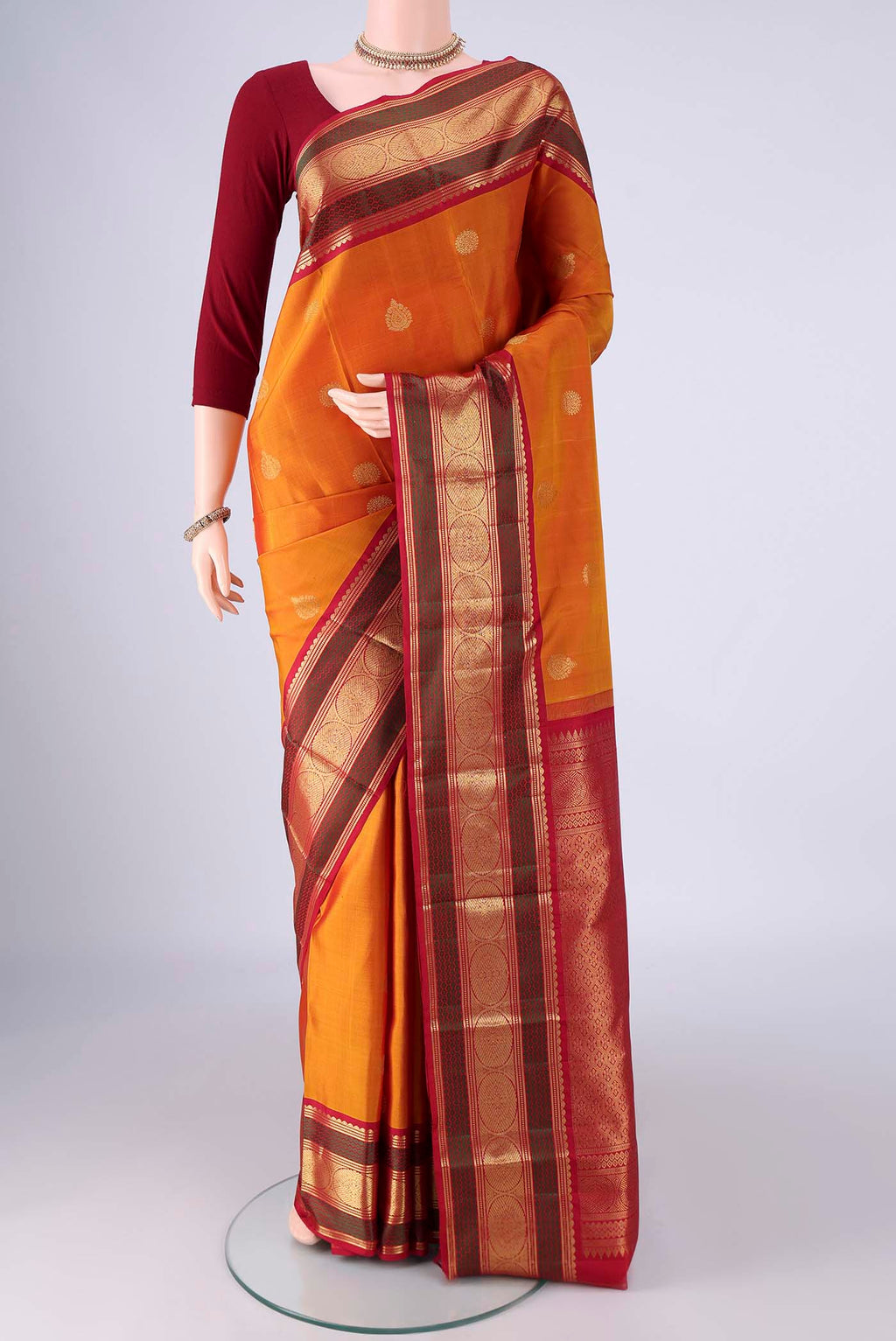 Mustard Kanchipuram Silk Saree with Zari Butta on the body and Zari And Thread Border.  displayed on a mannequin