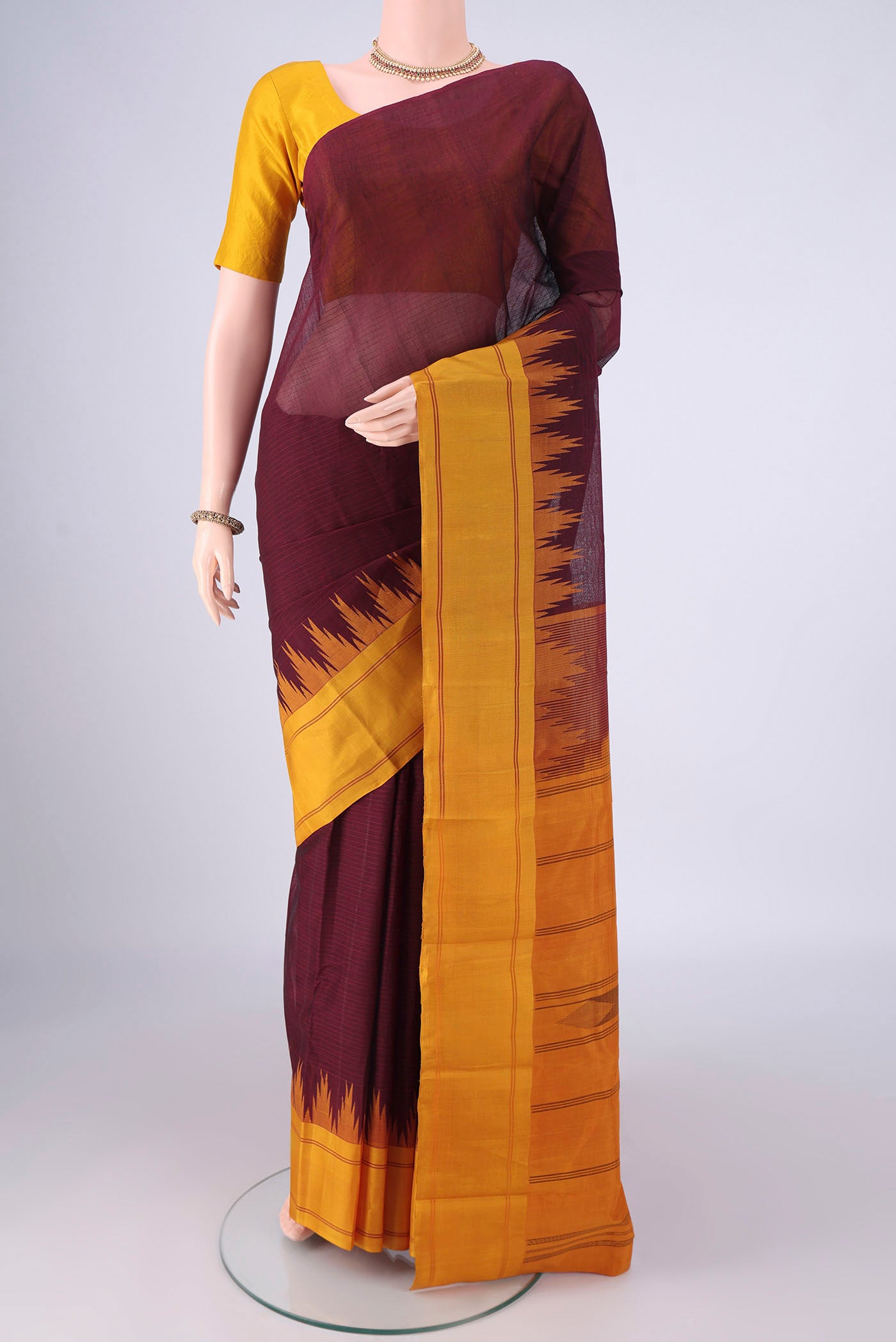Maroon Kanchi Cotton Saree with Plain Body and Temple Border.  displayed on a mannequin